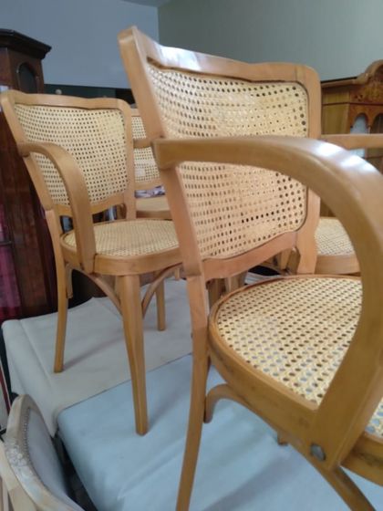 Silla tejida con cojín gris claro en una habitación con baldosas estampadas en el suelo y muebles de madera.