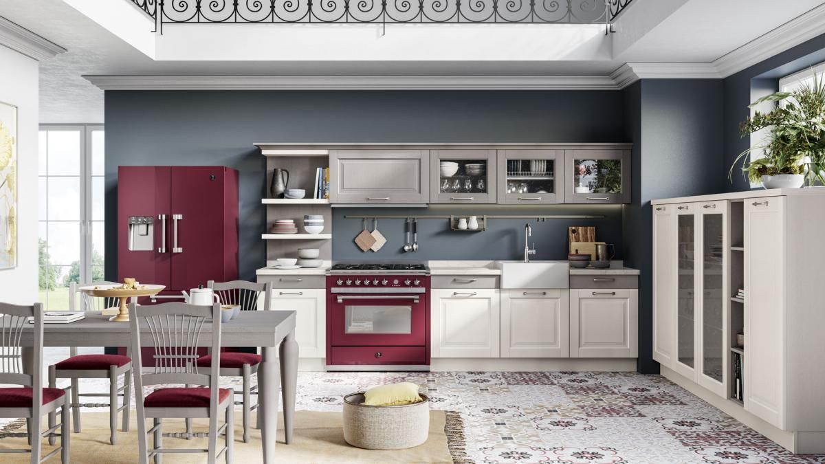 Una cucina con mobili bianchi ed elettrodomestici rossi e un tavolo da pranzo e sedie.