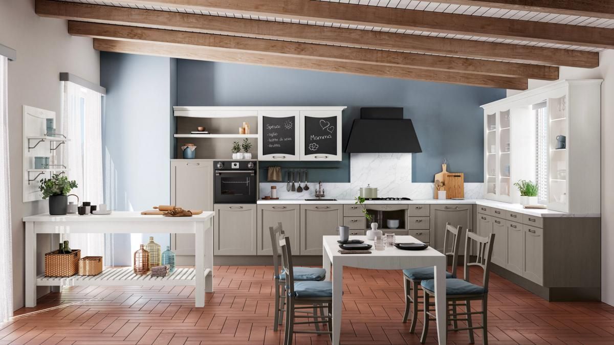 Una cucina con mobili bianchi, tavolo e sedie.