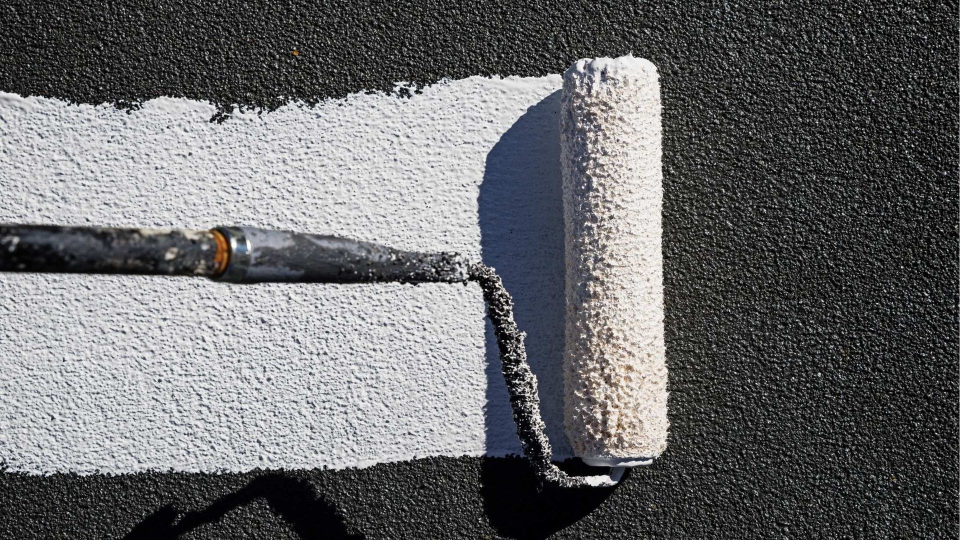 A paint roller is being used to paint a line on the ground.