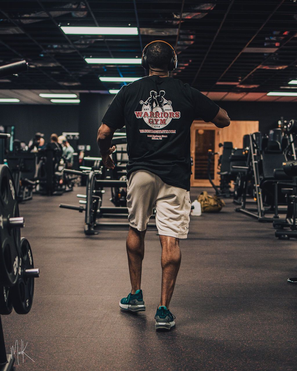 A man wearing headphones is running through a gym