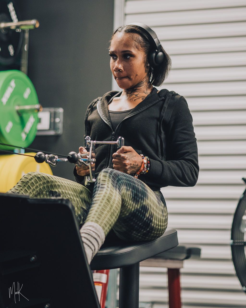 A woman wearing headphones is sitting on a rowing machine in a gym.