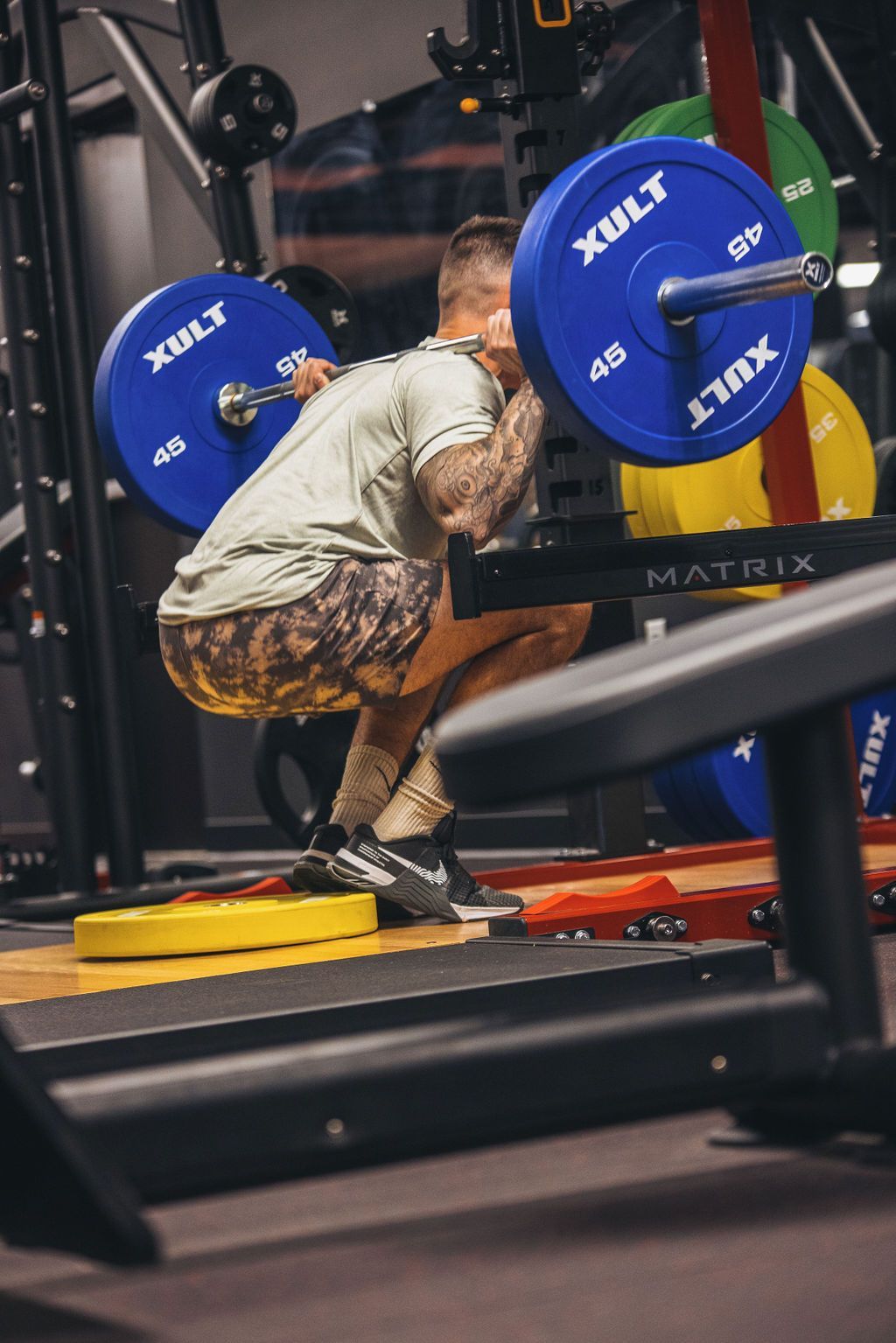 A man is squatting with a barbell in a gym.