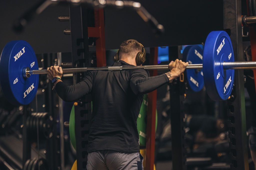 A man is squatting with a barbell in a gym.
