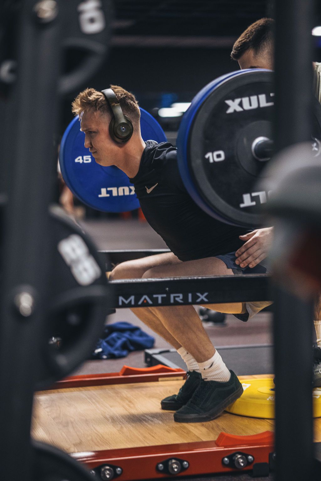A man is squatting with a barbell in a gym.