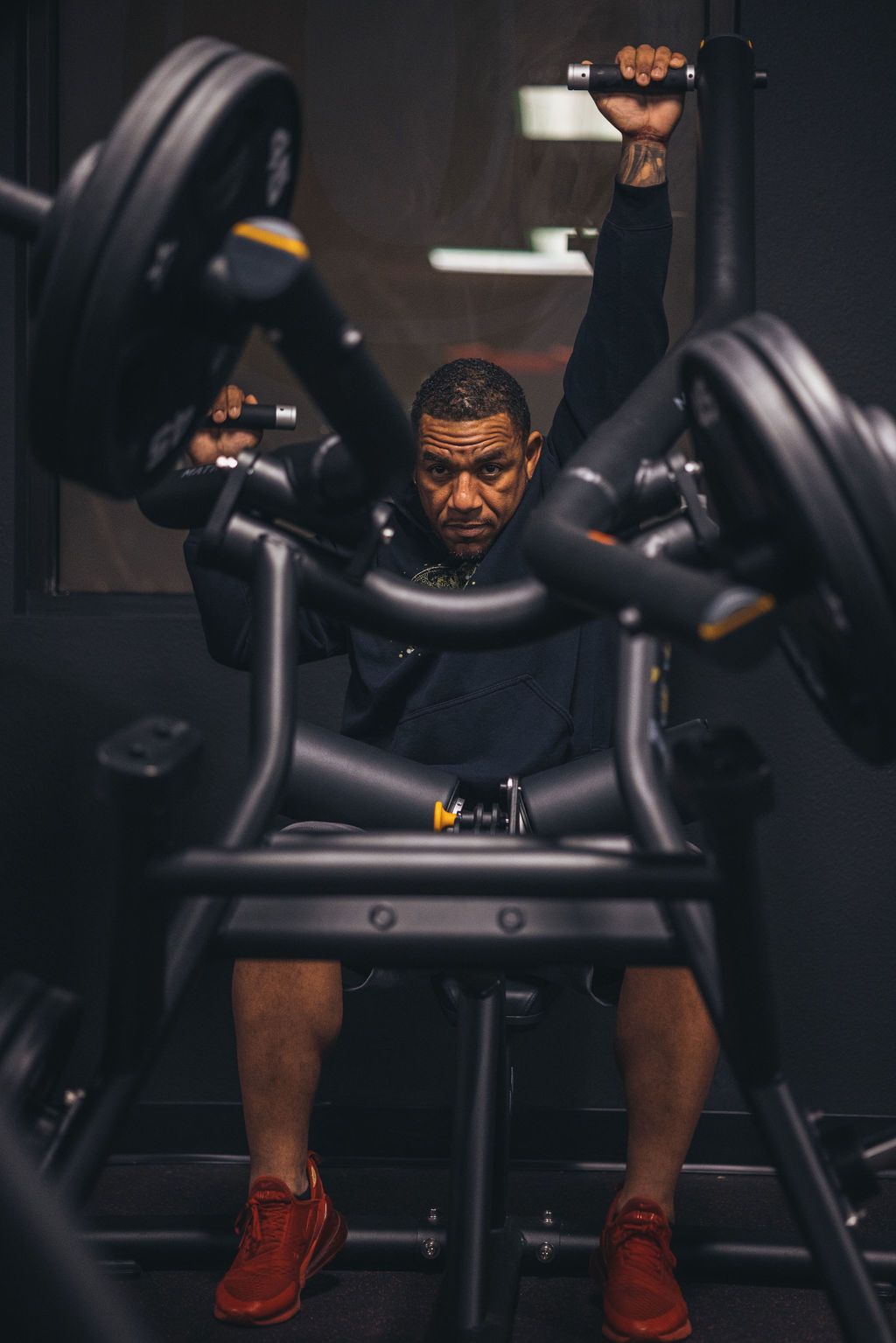 A man is sitting on a machine in a gym lifting weights.