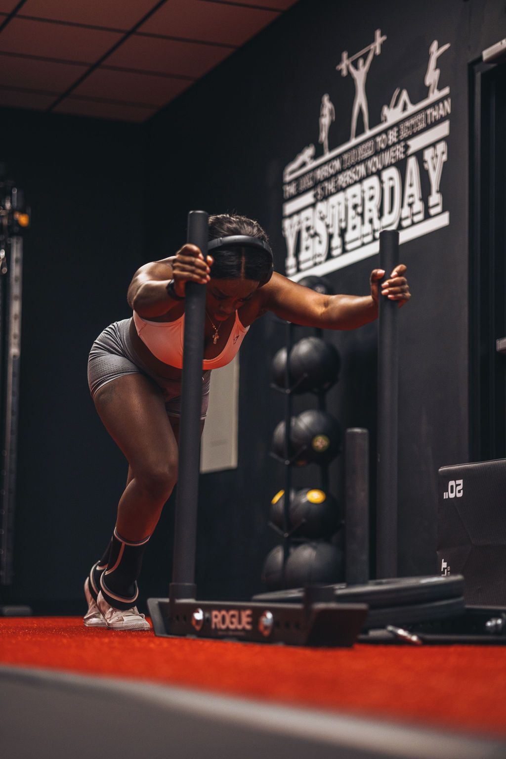 A woman is pushing a sled in a gym.