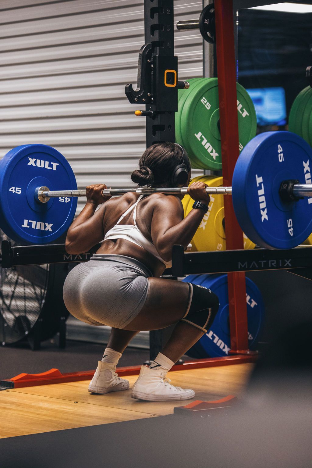 A woman is squatting with a barbell in a gym.