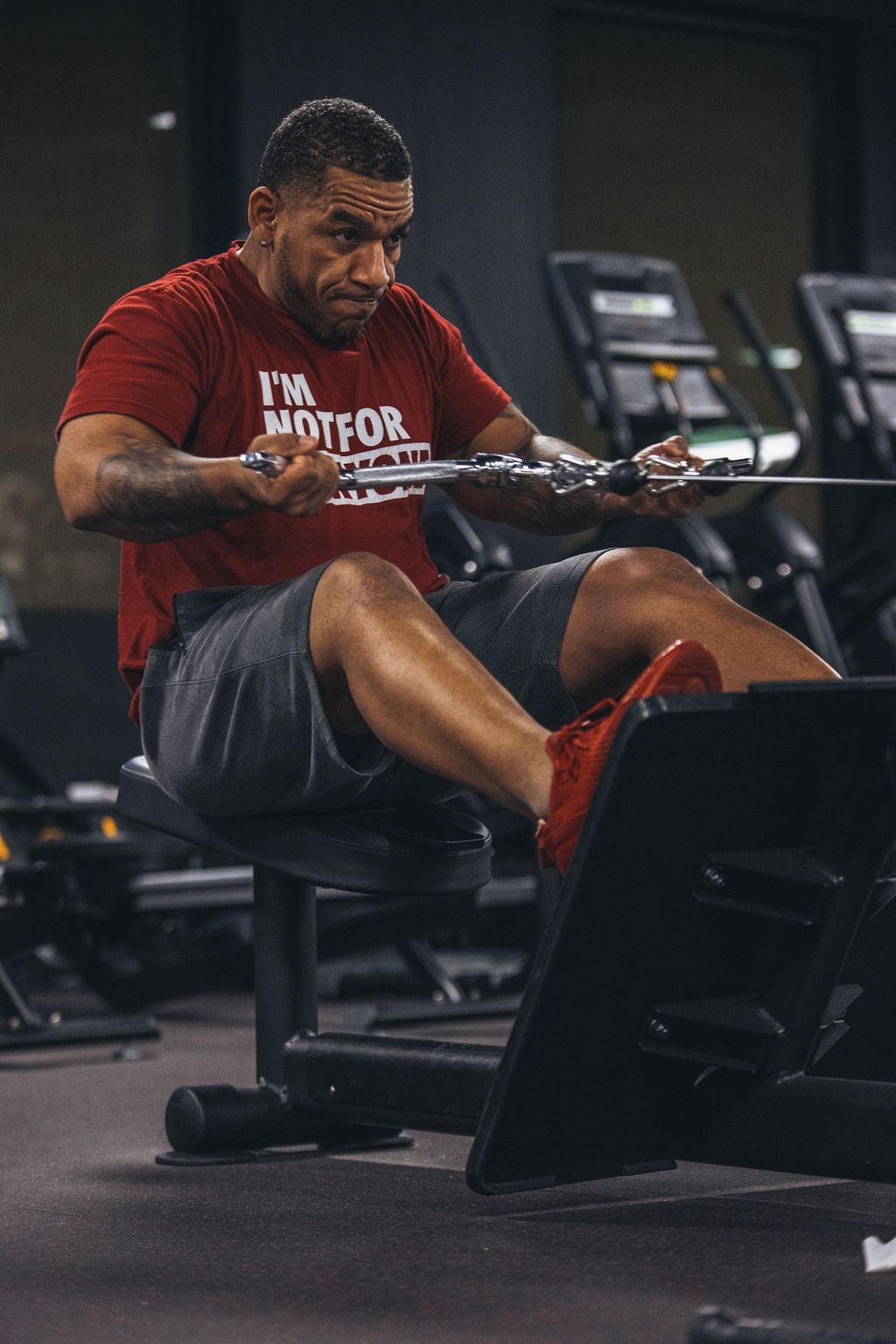 A man is sitting on a rowing machine in a gym.
