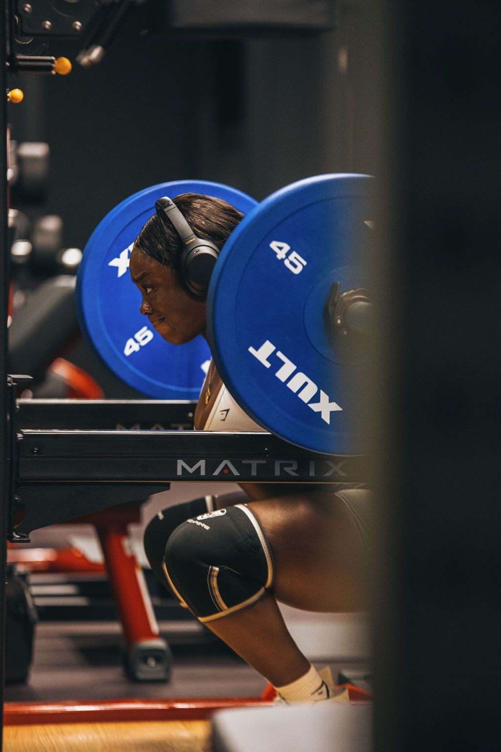 A woman is squatting with a barbell on her back in a gym.
