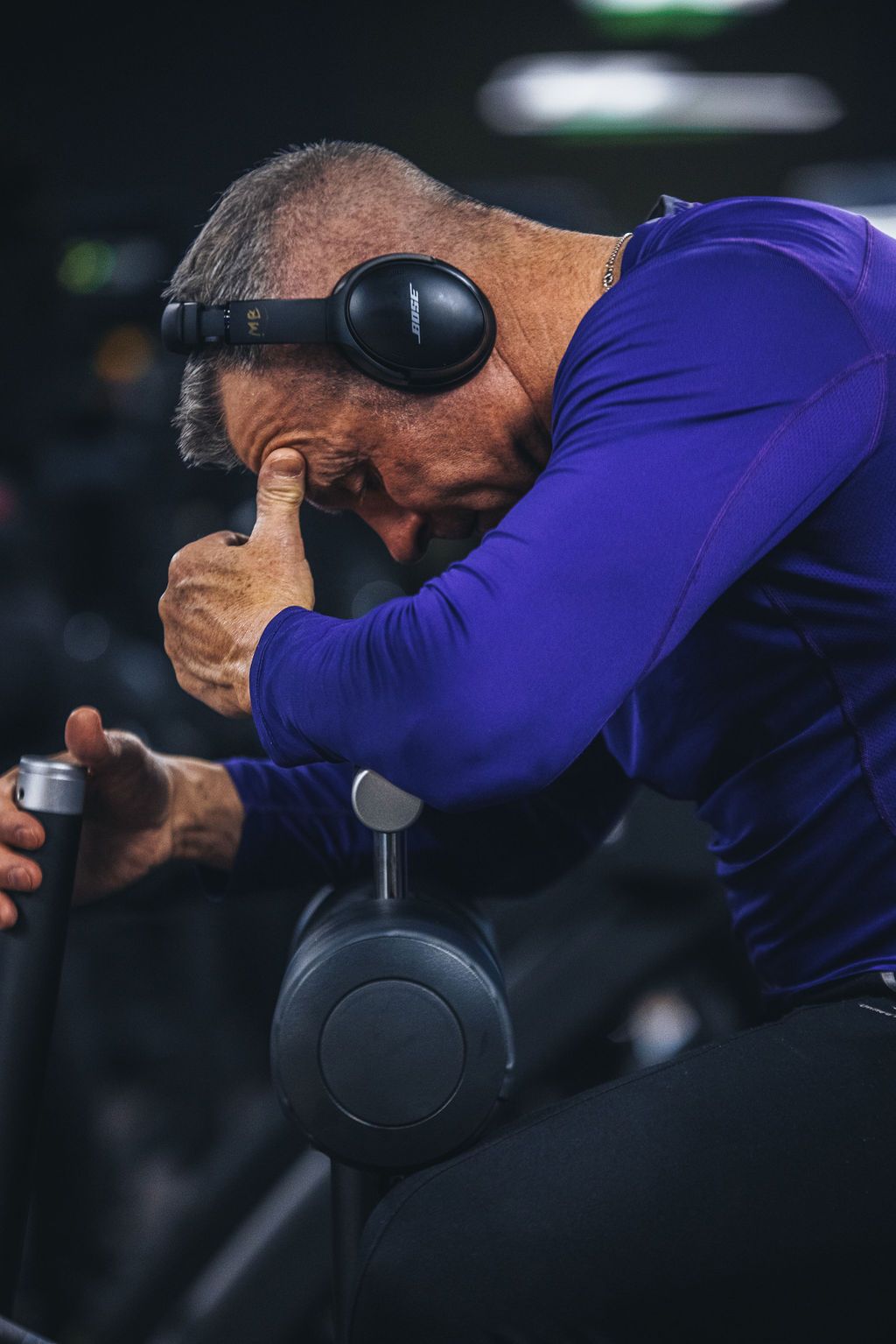 A man wearing headphones is lifting a dumbbell in a gym.