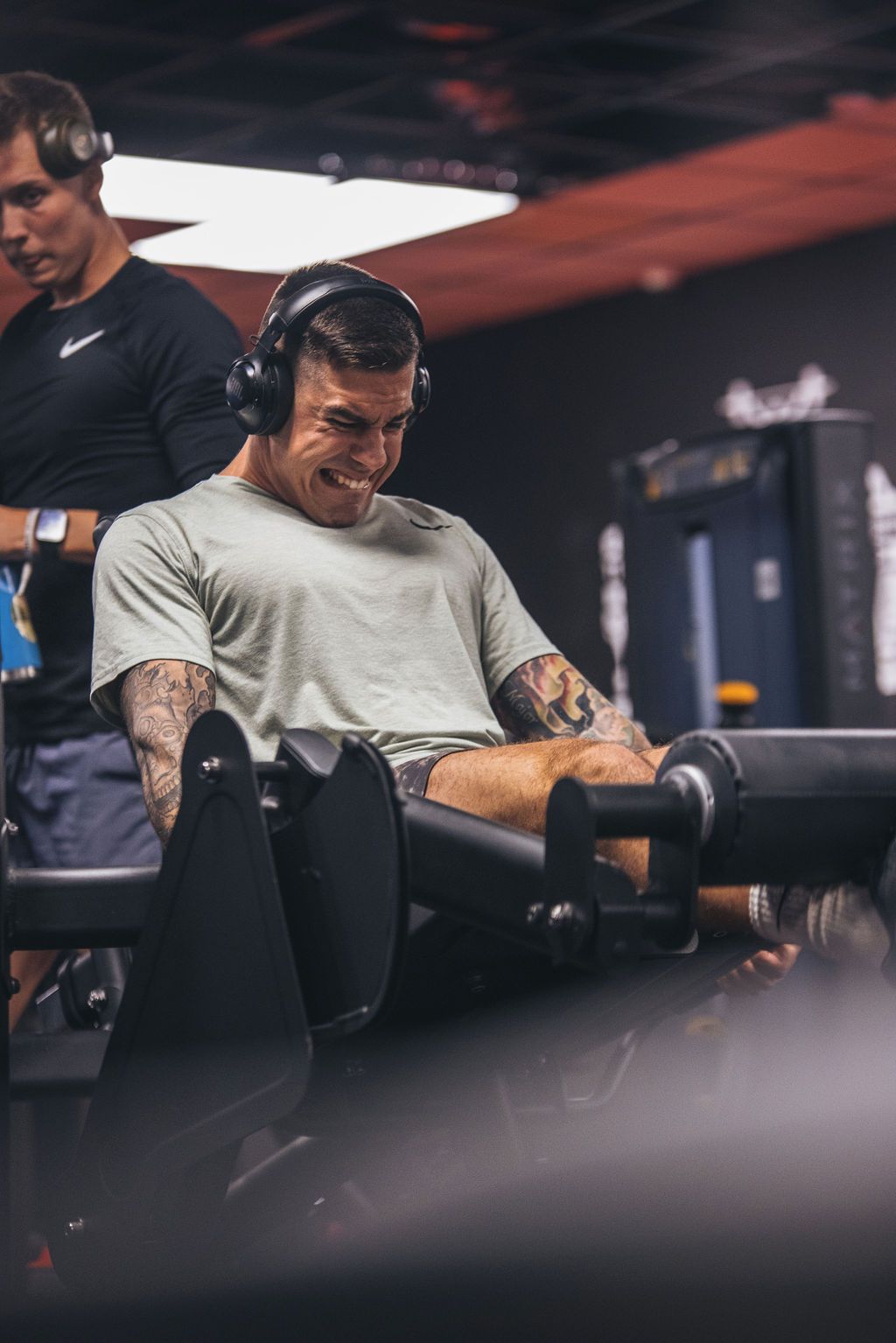A man wearing headphones is sitting on a machine in a gym.