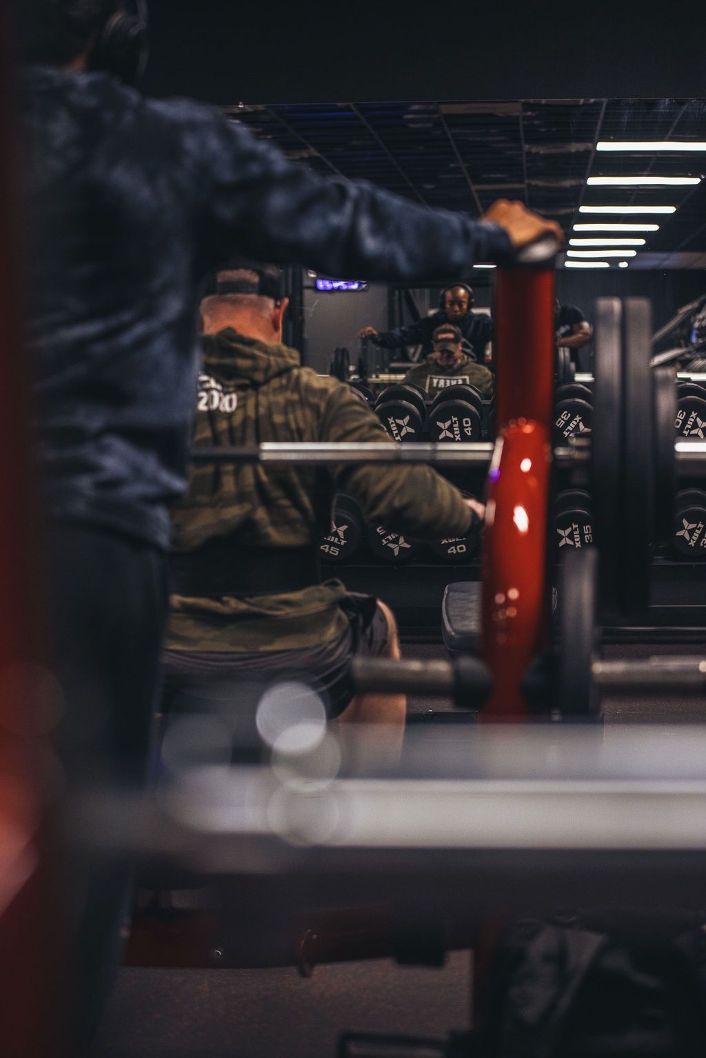 A man is lifting a barbell in a gym.