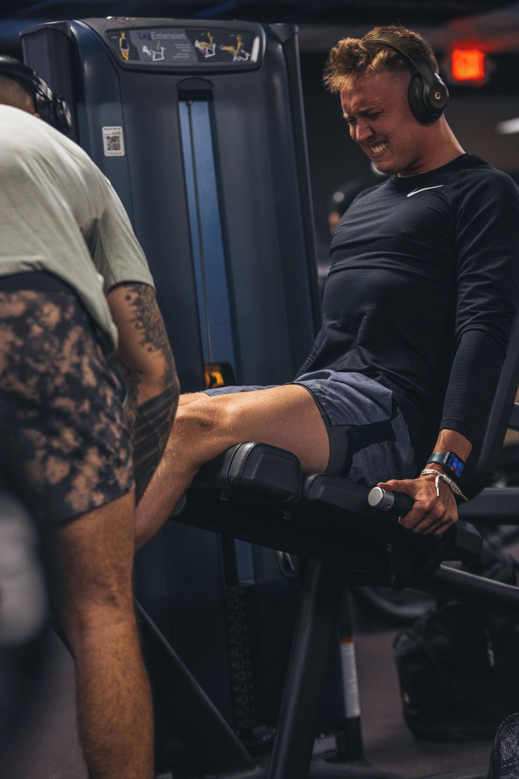 A man is stretching his leg on a machine in a gym.