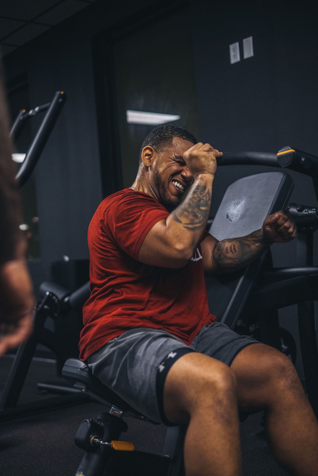 A man is sitting on a machine in a gym.
