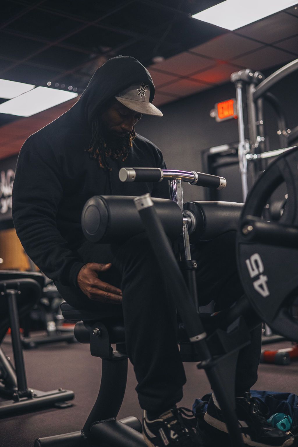 A man is sitting on a machine in a gym.