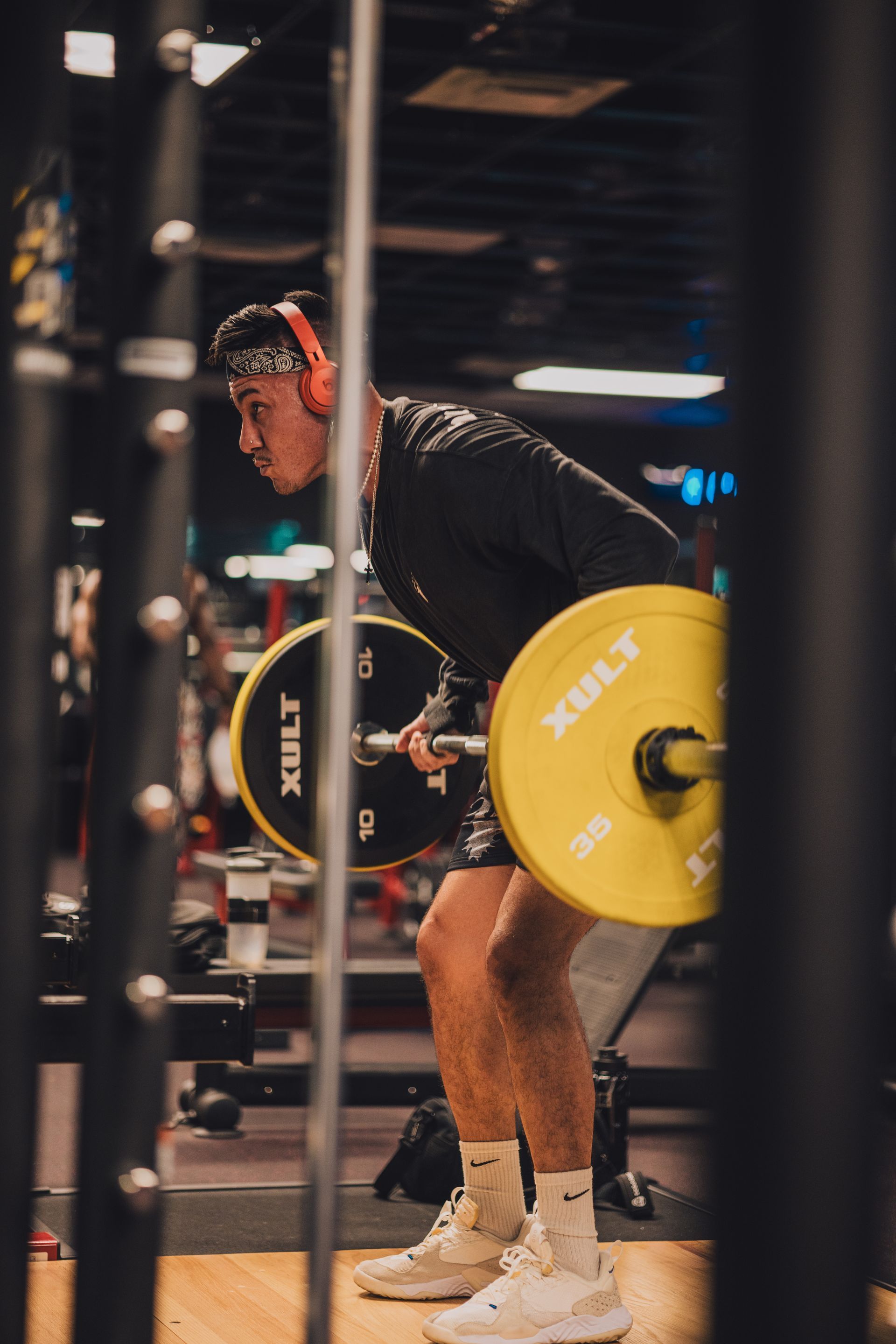 A man is lifting a barbell in a gym.