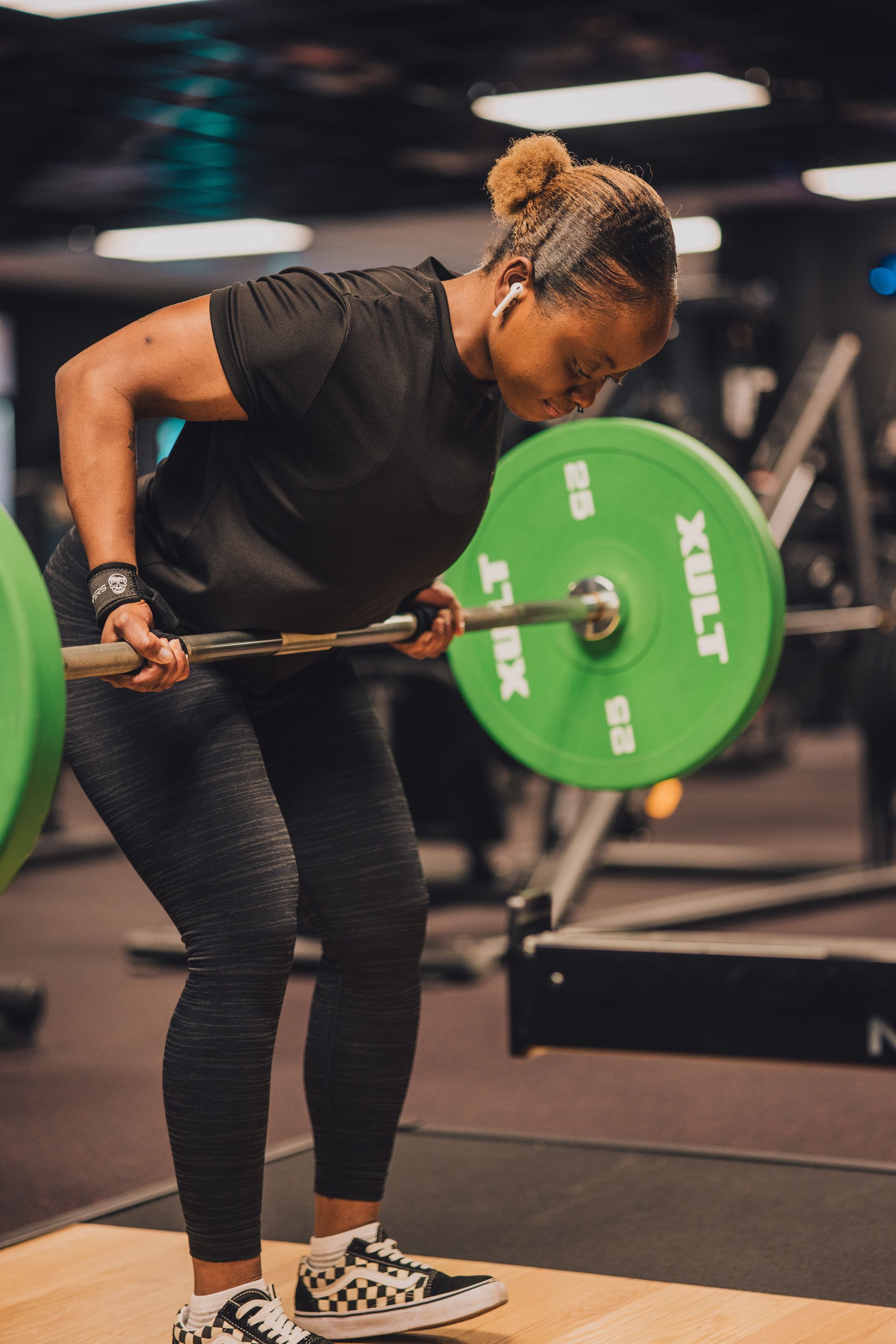 A woman is lifting a barbell in a gym.