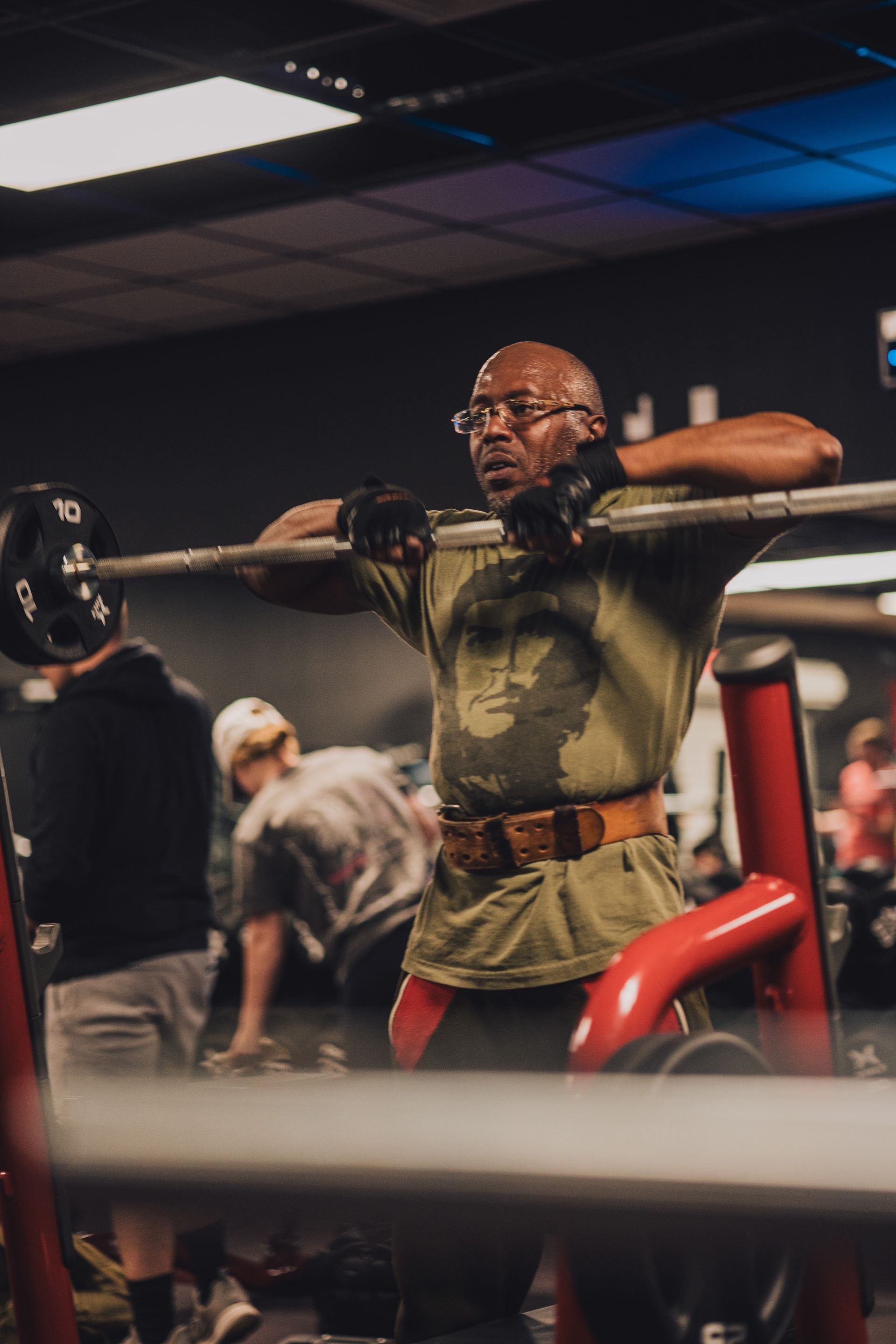 A man is squatting with a barbell in a gym.