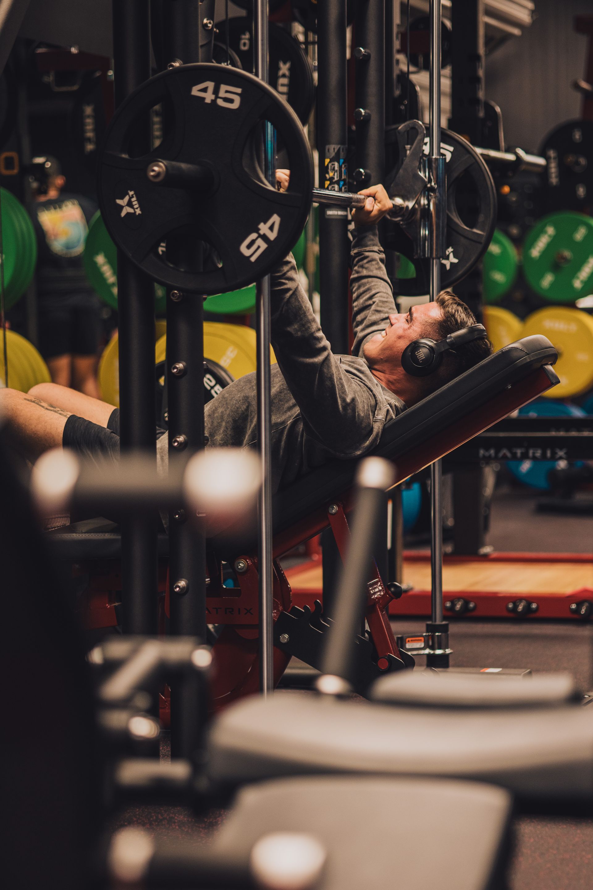A man is lifting a barbell in a gym.
