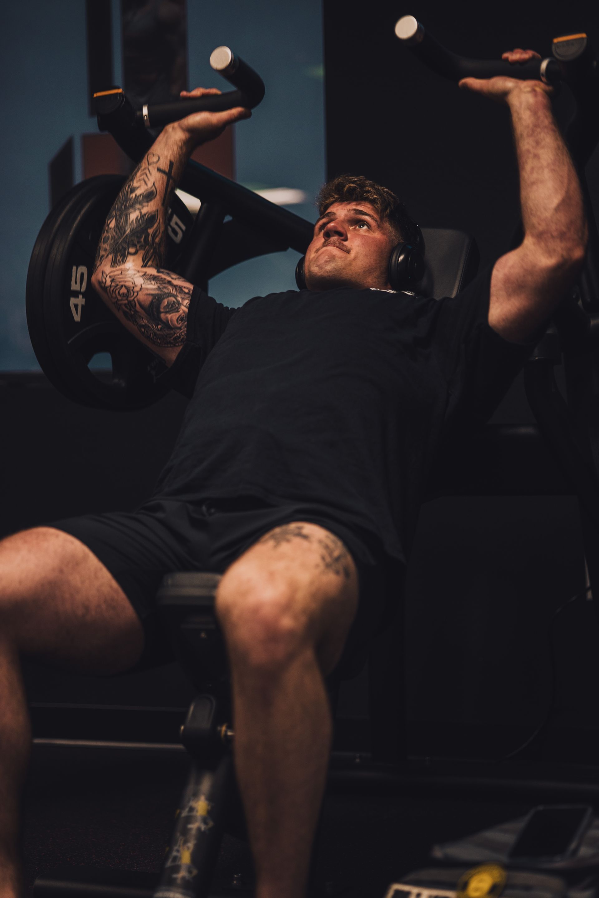 A man is sitting on a bench in a gym lifting a barbell.