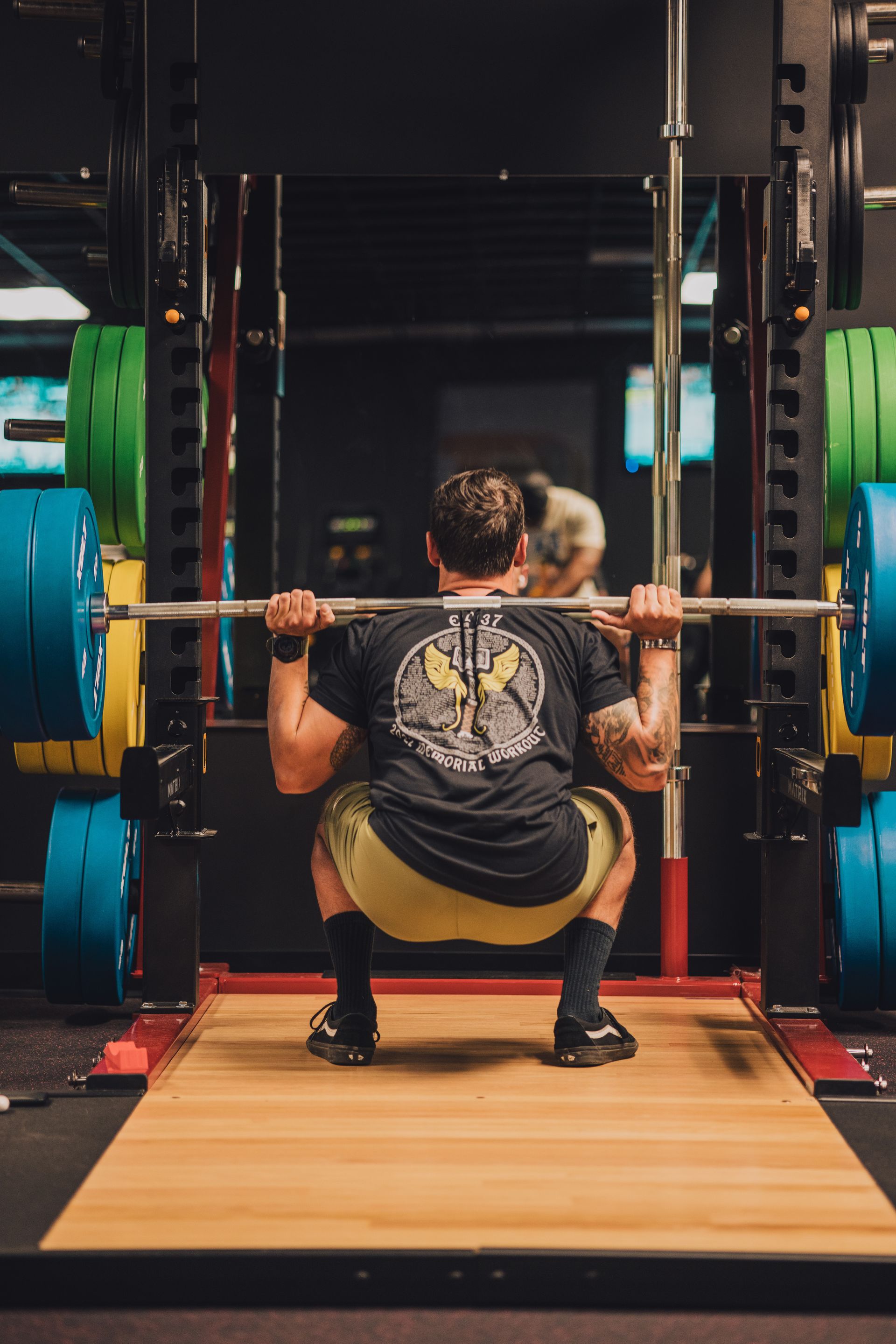 A man is squatting with a barbell in a gym.