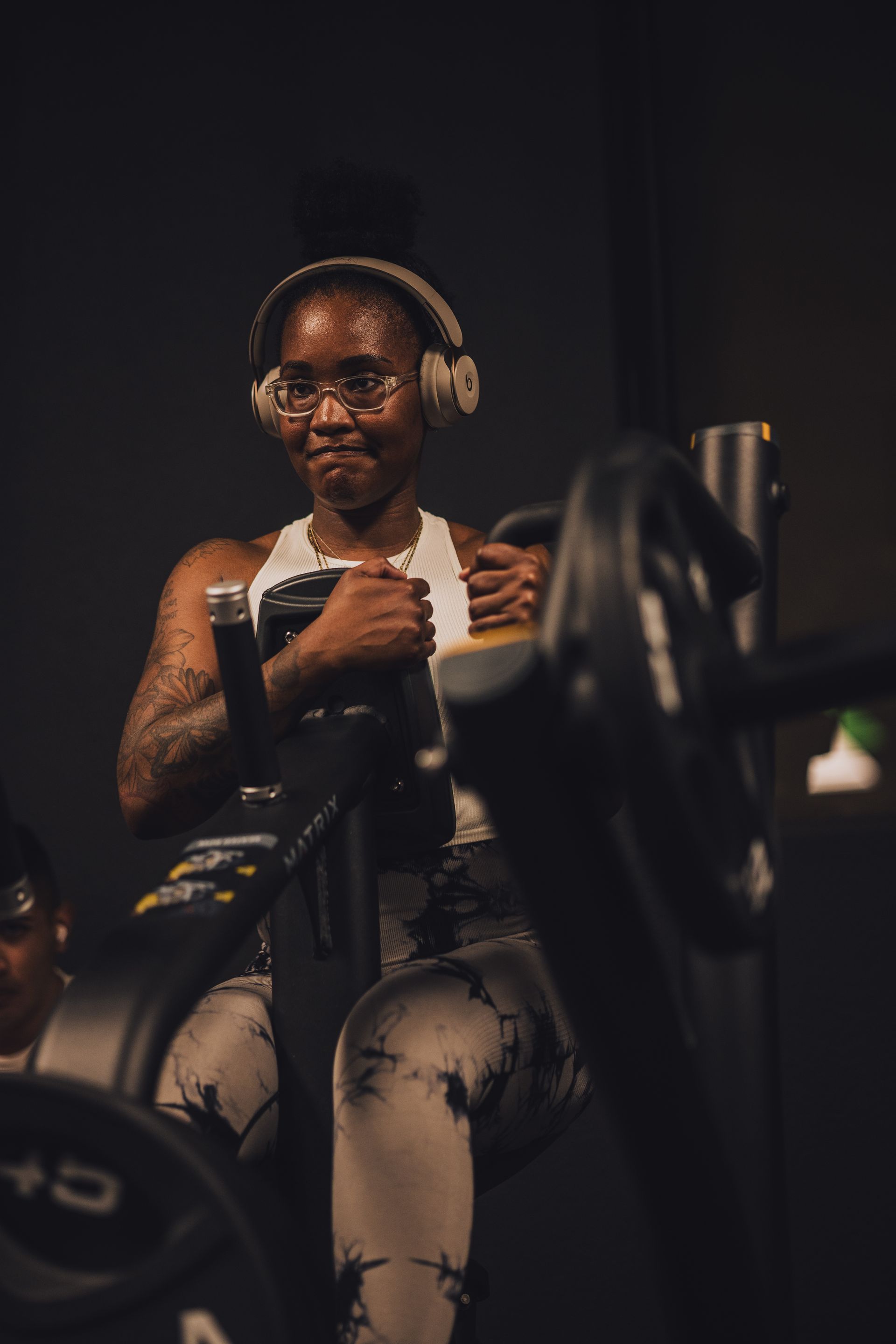 A woman wearing headphones is riding an exercise bike in a gym.