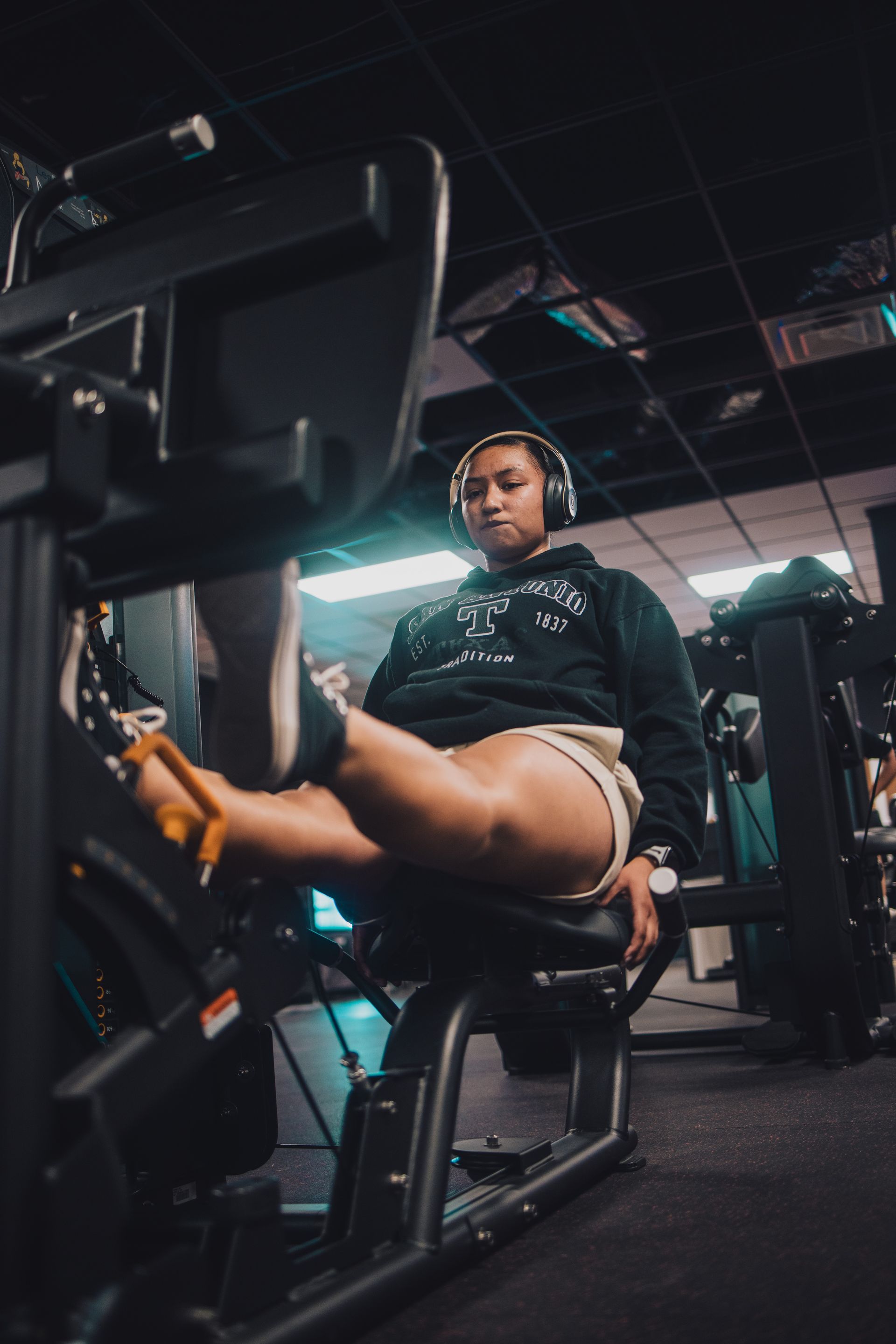 A woman is sitting on a machine in a gym with her legs crossed.