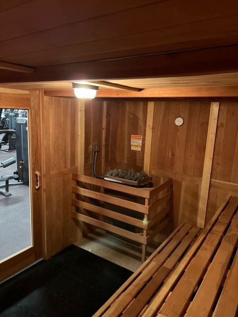 A wooden sauna with a black mat in a gym.