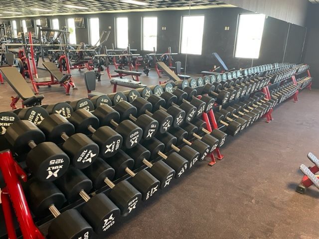 A gym filled with lots of dumbbells and benches