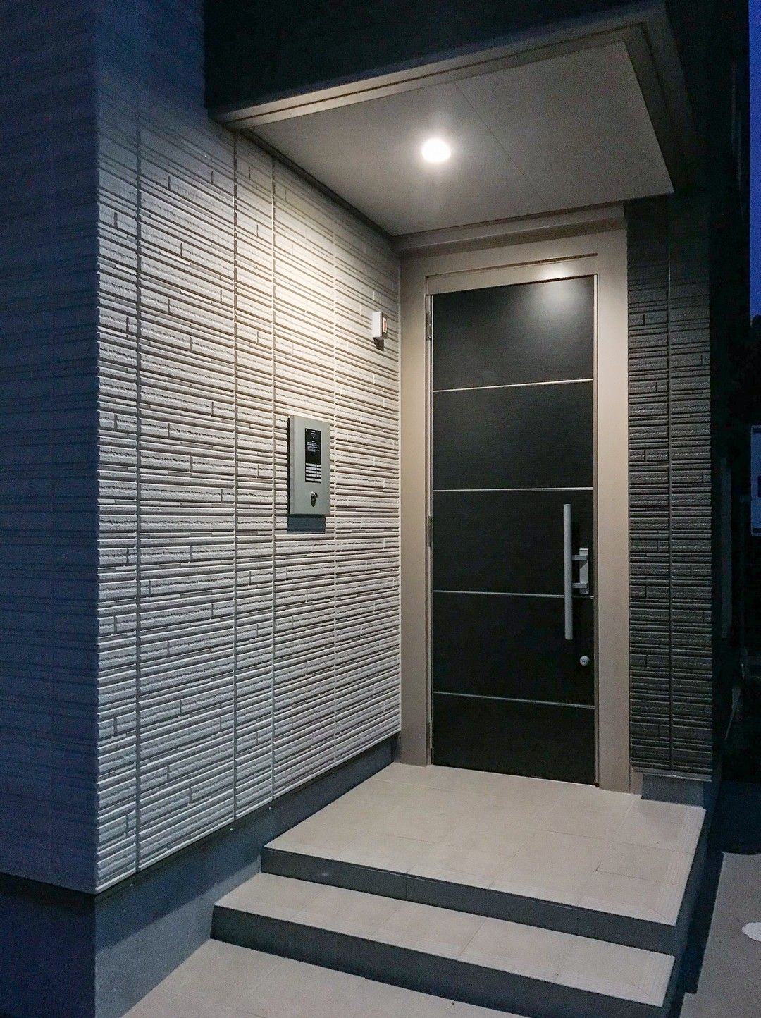 Una porta nera con una maniglia argentata si trova sul lato di un edificio