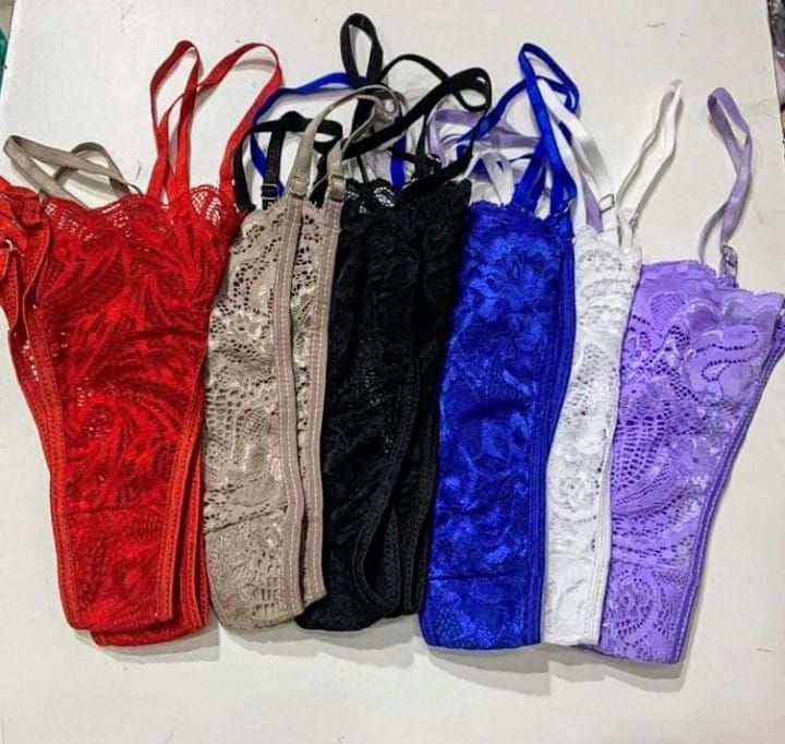 Seis tangas de encaje en rojo, tostado, negro, azul, blanco y morado con tiras finas dispuestas sobre una superficie.