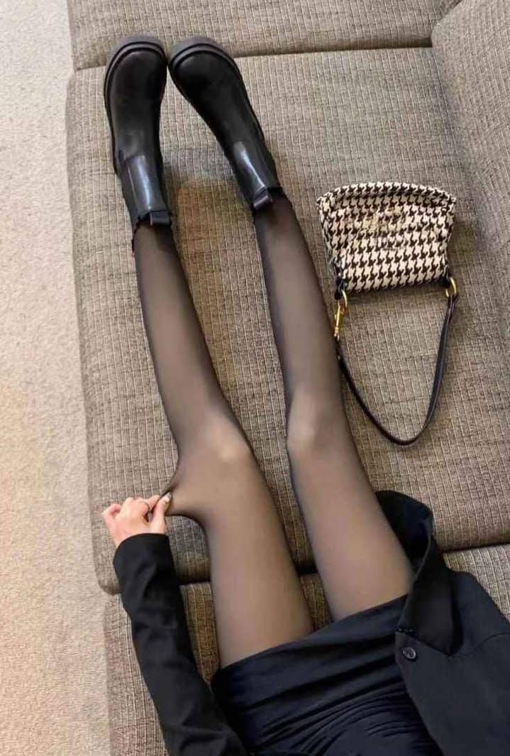 Mujer con botas negras, medias negras transparentes y un vestido, con un bolso en un sofá.
