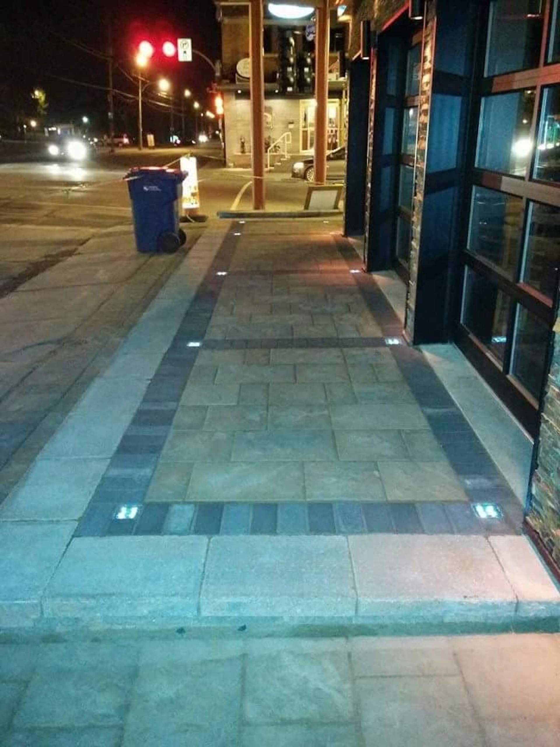 Un trottoir avec une poubelle bleue au milieu