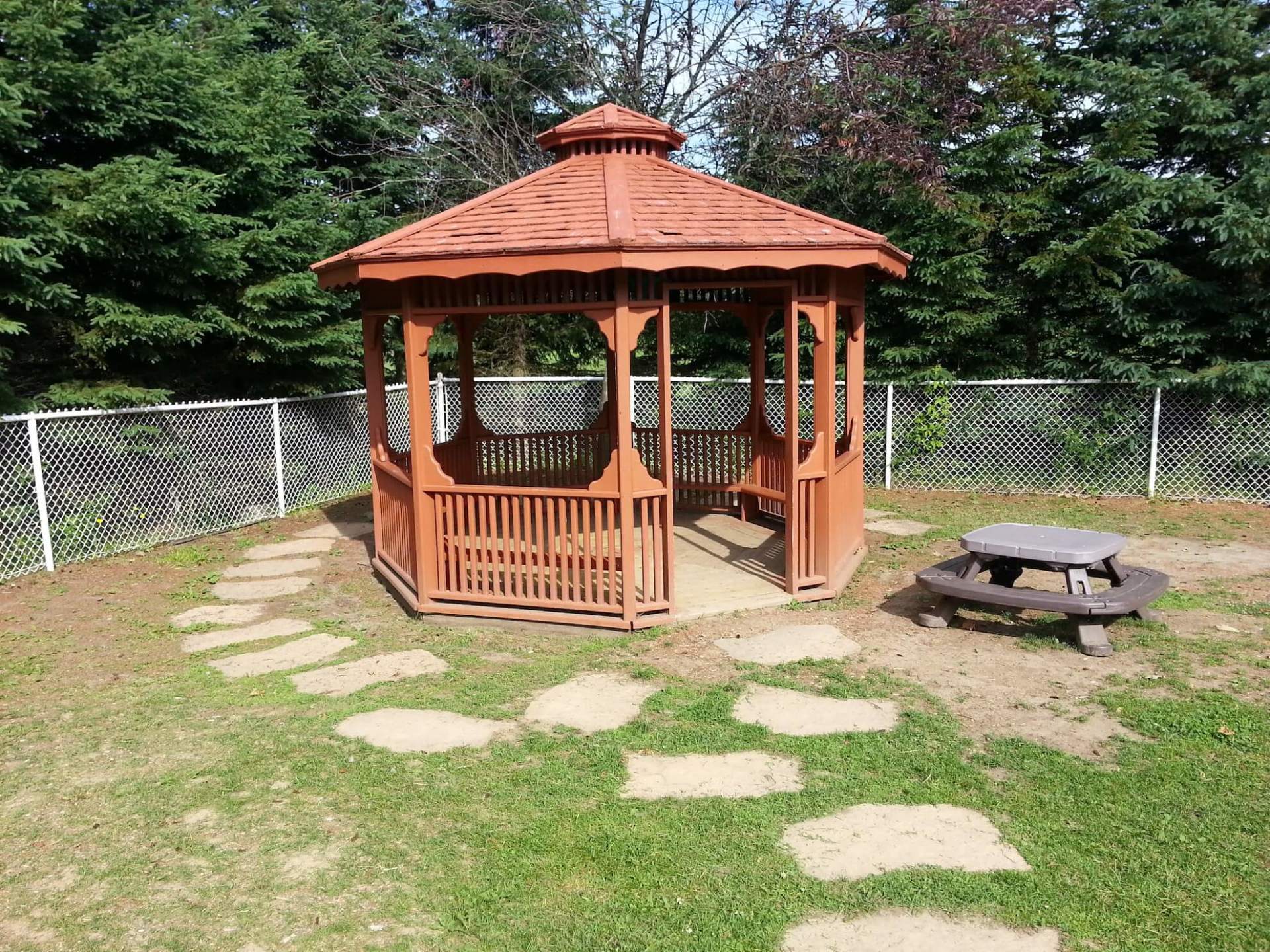 Un gazebo en bois avec une table de pique-nique devant