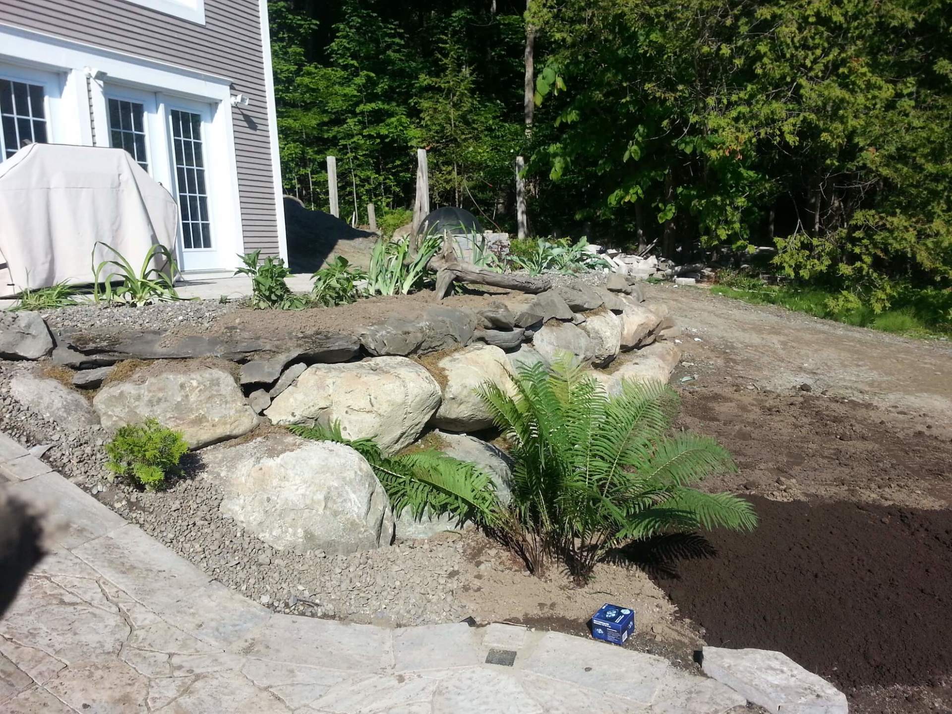 Un mur de pierre est en construction devant une maison