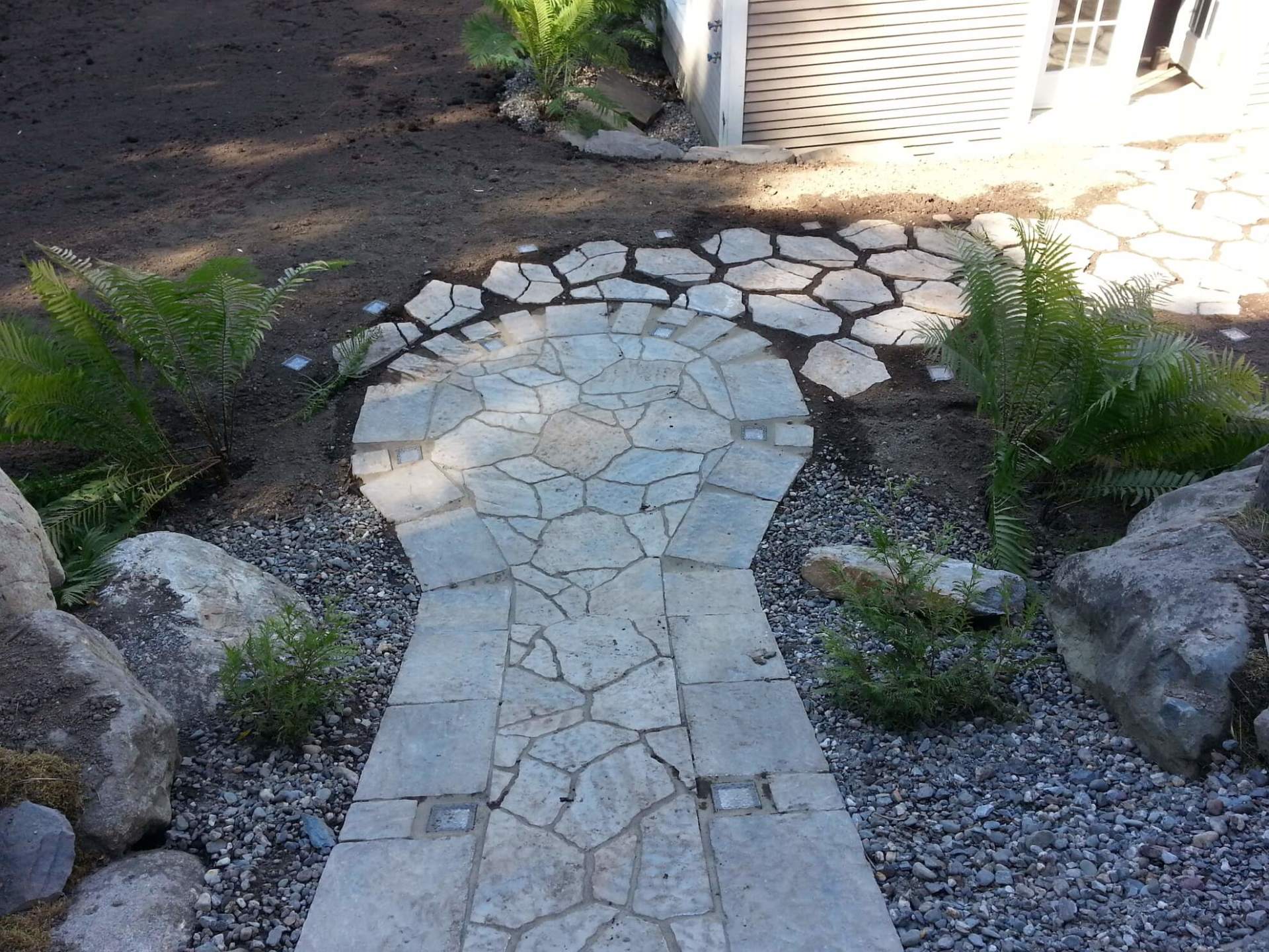 Une allée en pierre est entourée de rochers et de plantes