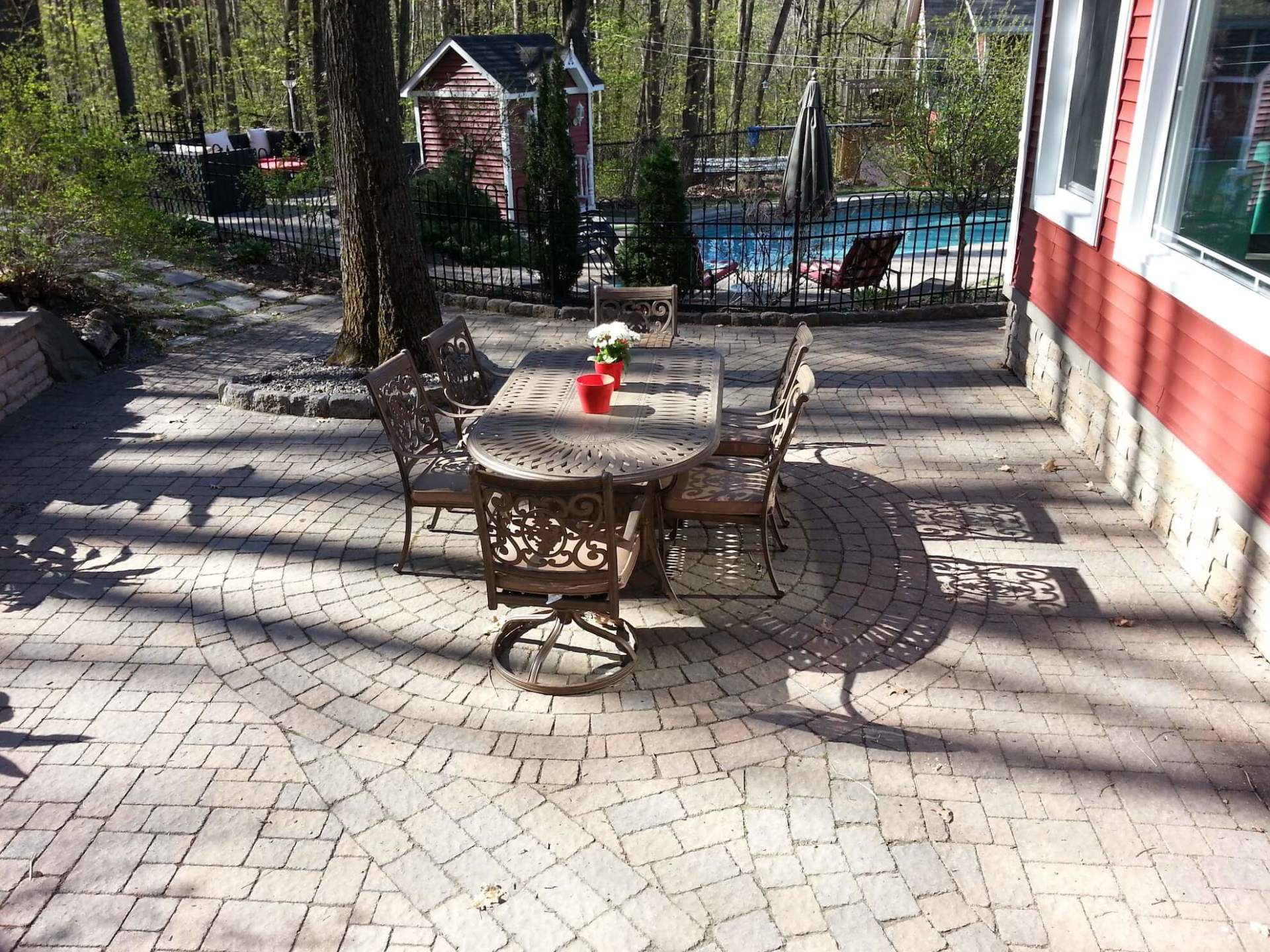 Un patio avec une table et des chaises et une piscine en arrière-plan
