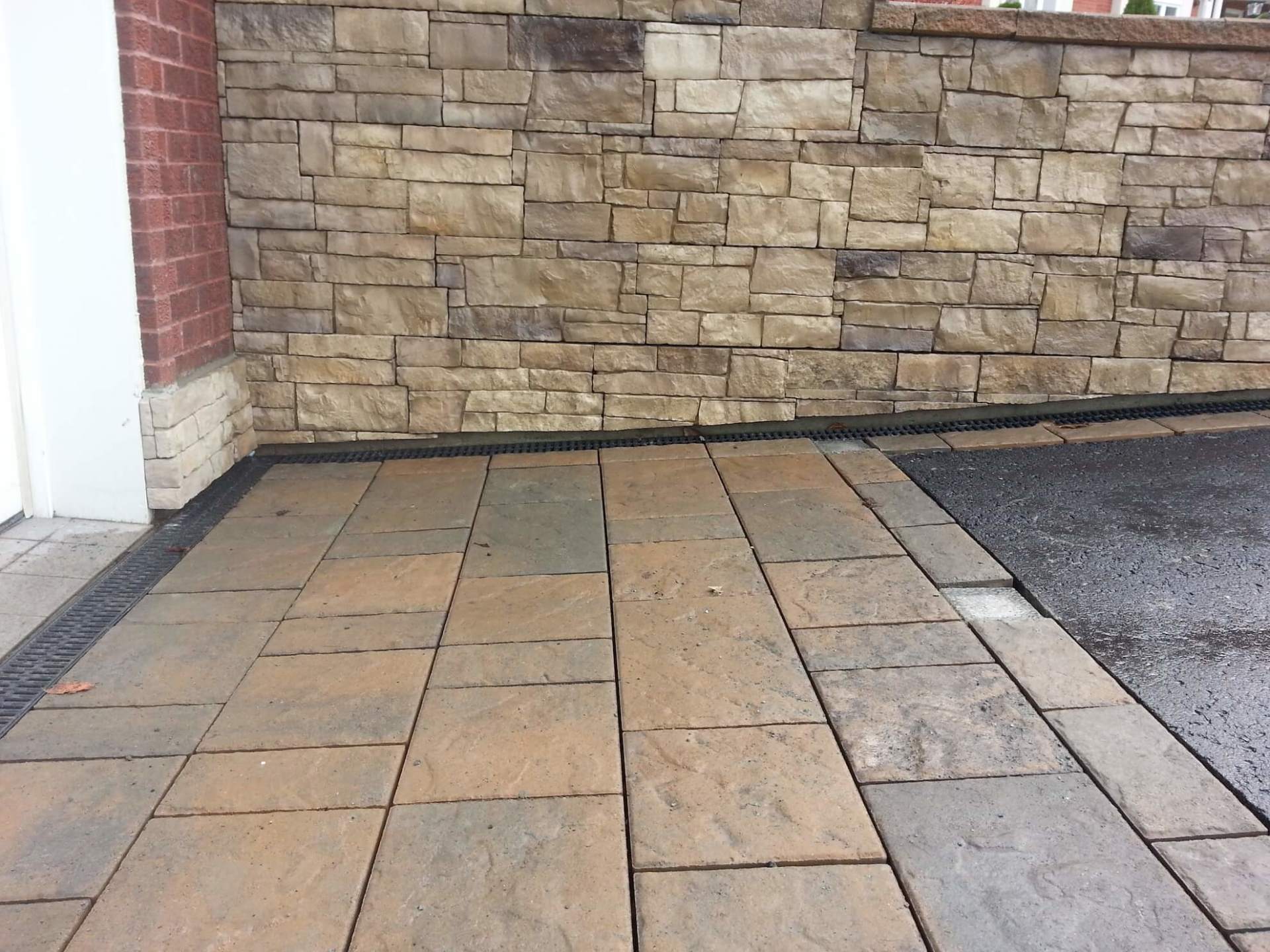 Un mur de pierre avec une allée en briques devant