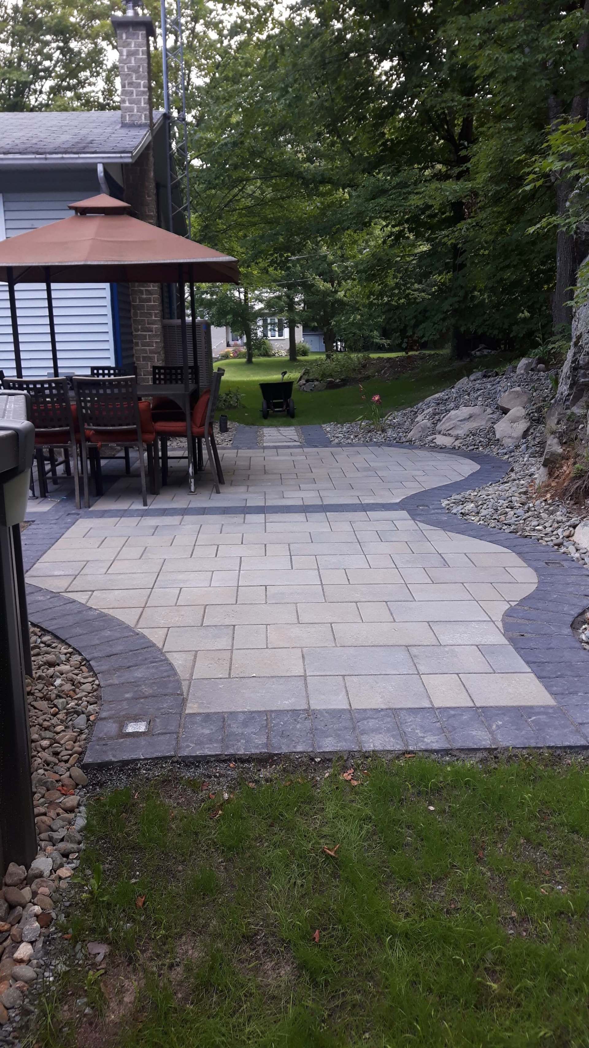 Un patio avec un gazebo et une table et des chaises dans l'arrière-cour d'une maison.