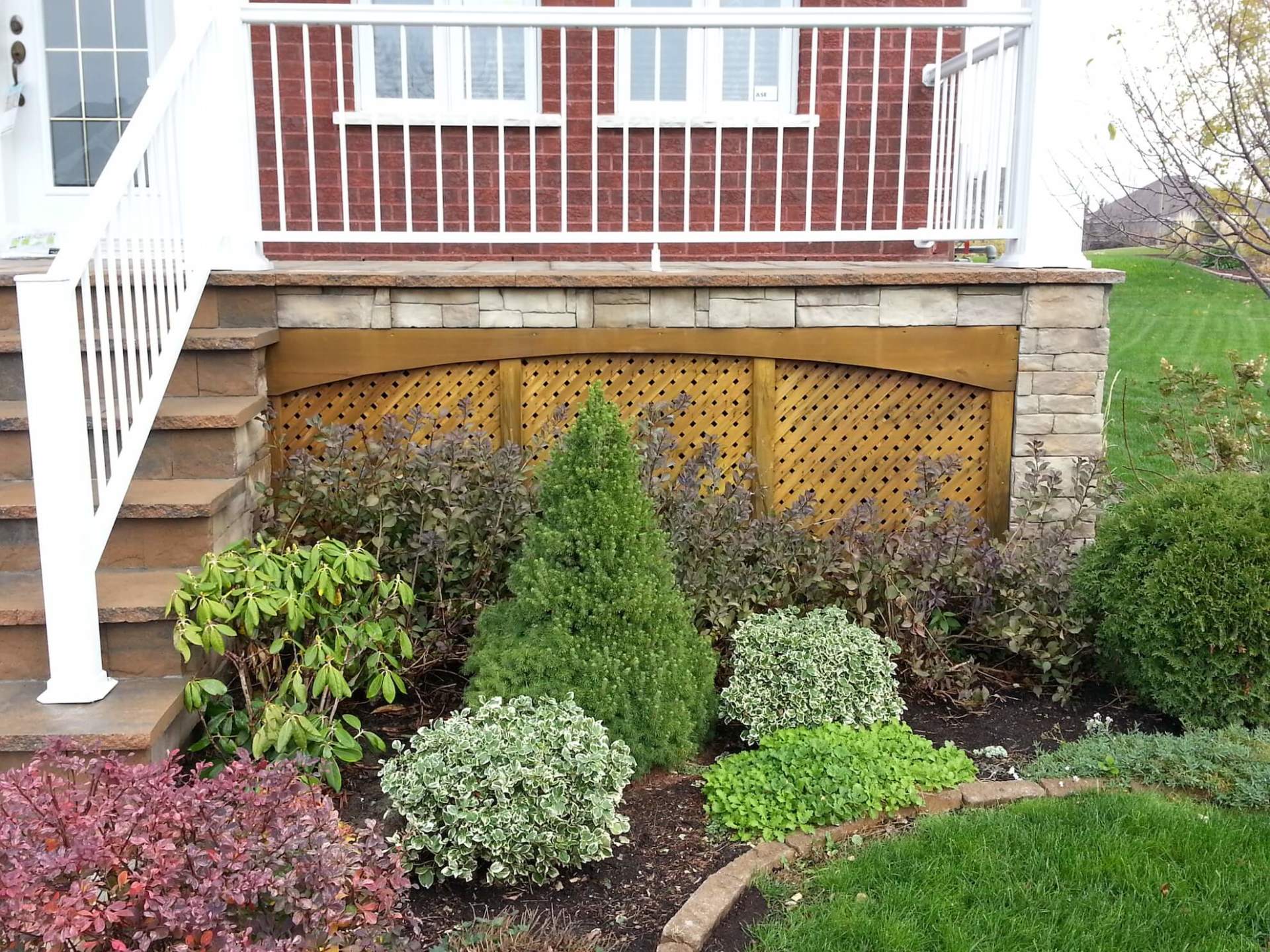 Une maison en briques avec une balustrade blanche et un jardin devant