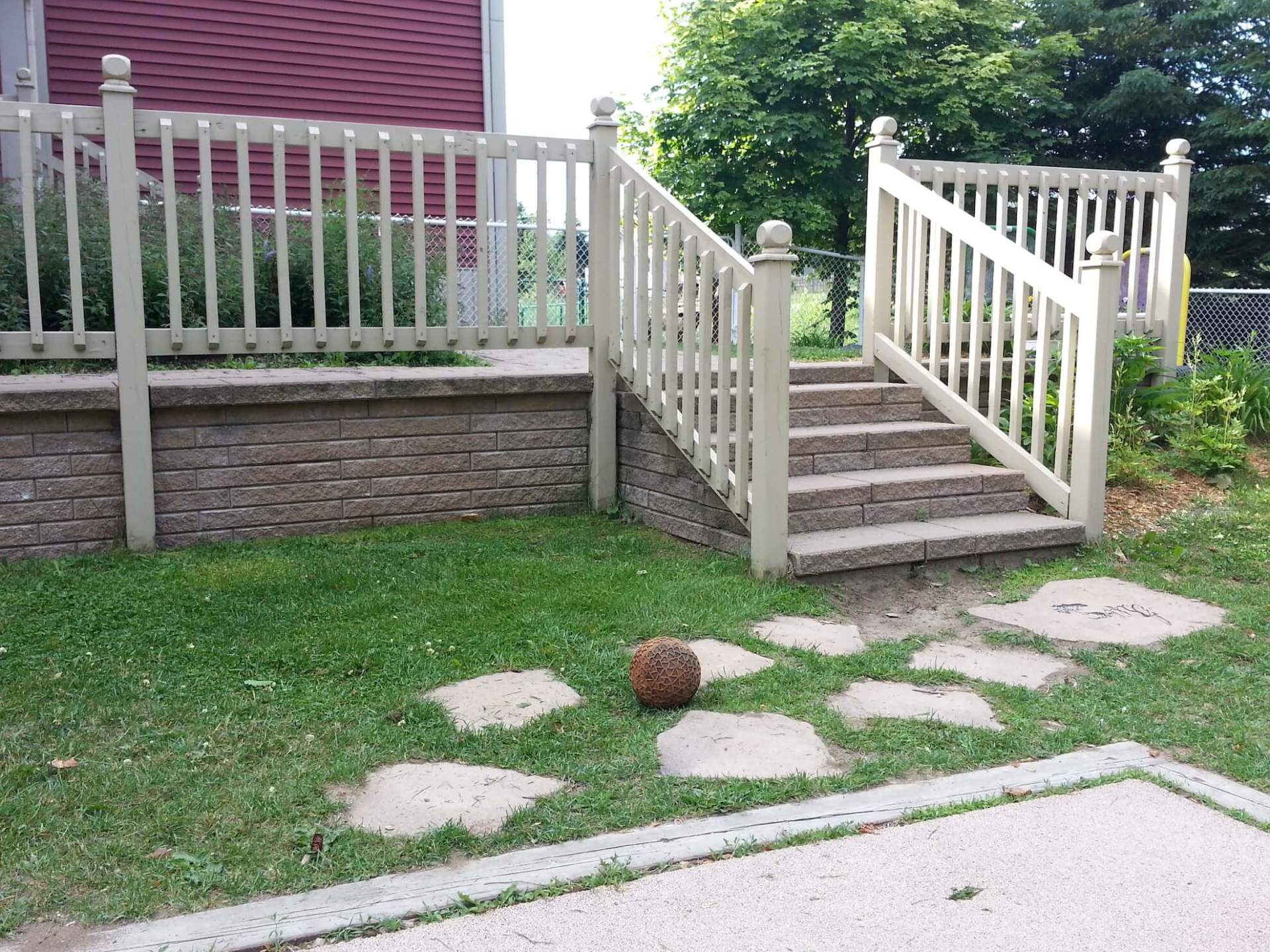 Une clôture blanche avec des escaliers et une balle dans l'herbe