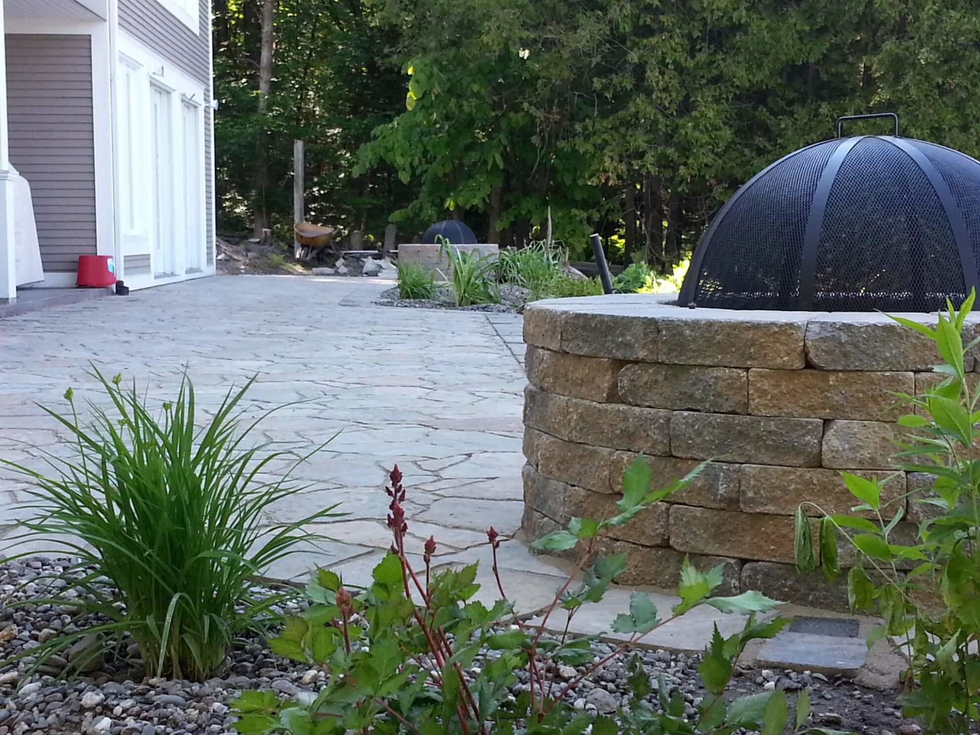 Un foyer se trouve au milieu d'un patio à côté d'une maison.