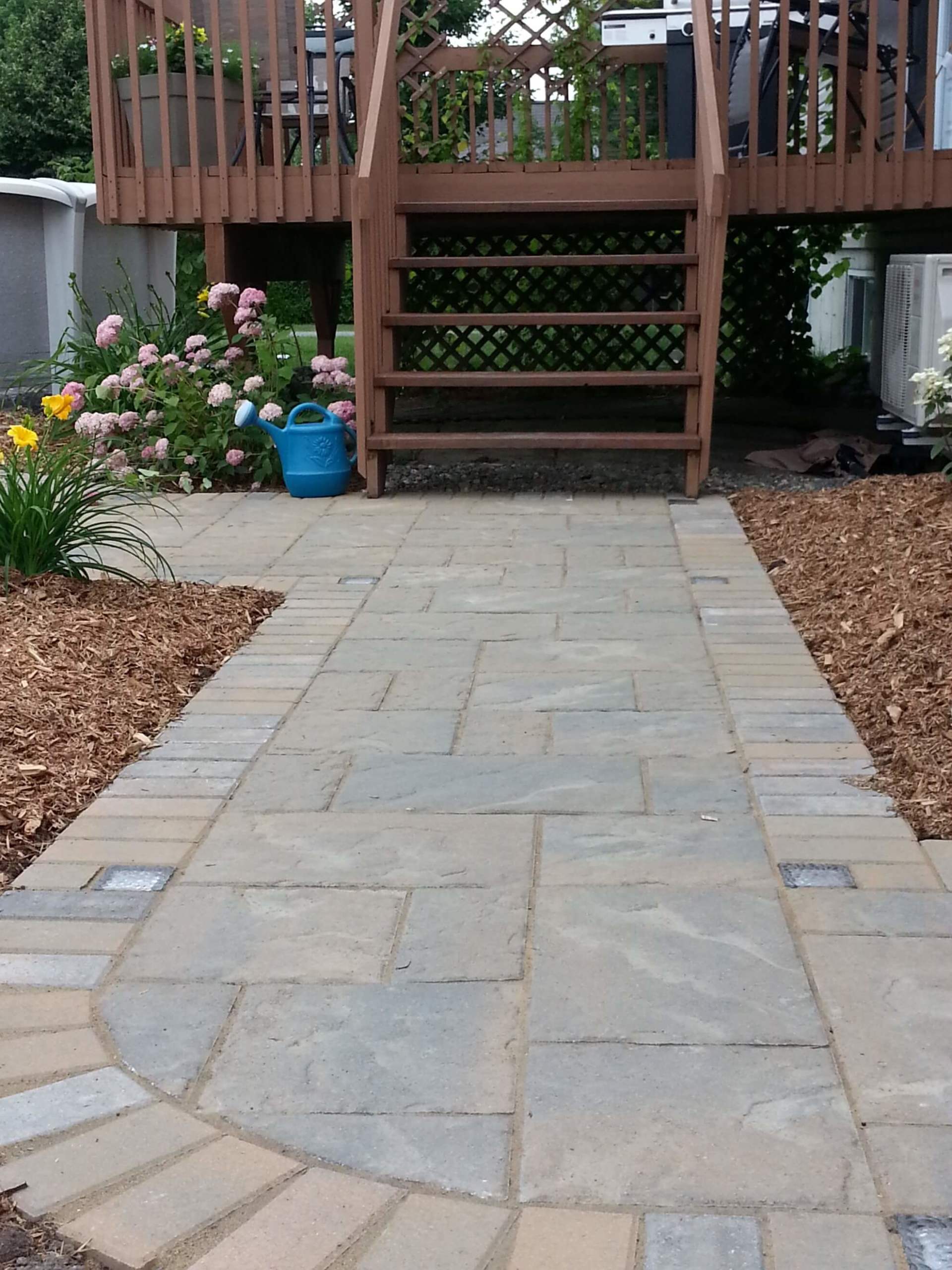 Une passerelle menant à une terrasse avec un arrosoir bleu sur le côté