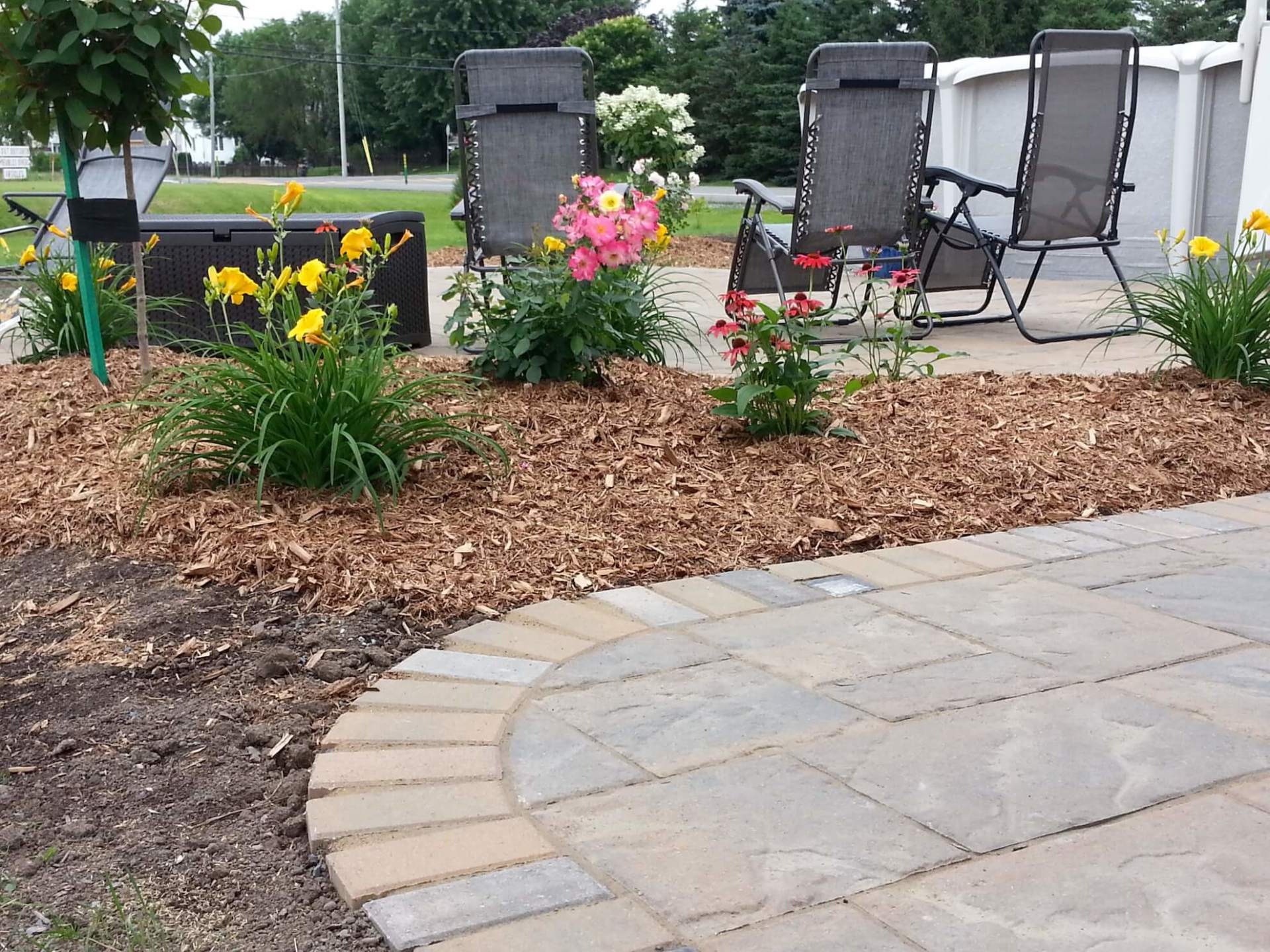 Un patio avec des chaises et des fleurs en arrière-plan