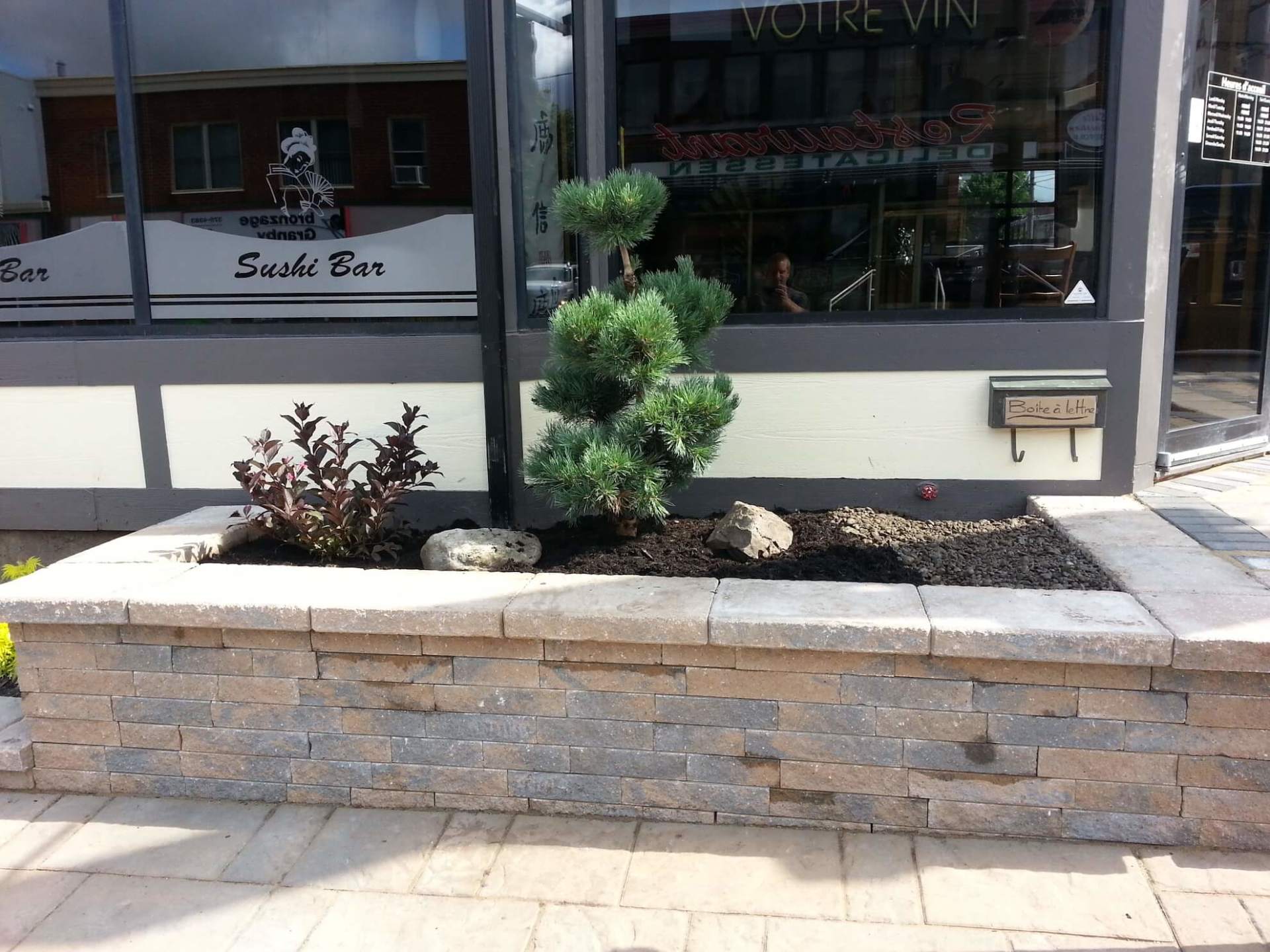 Une jardinière devant un bar à sushis avec un arbre dedans