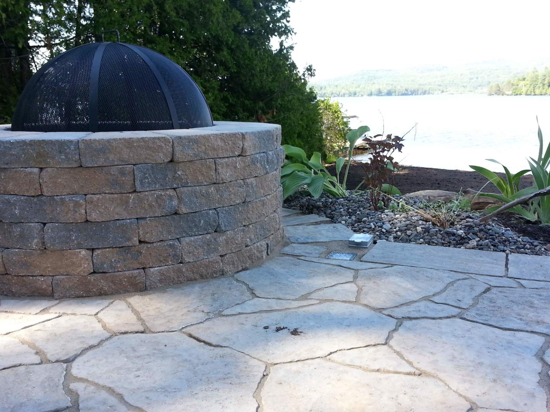Un foyer est entouré d'un mur de briques et d'un patio en pierre