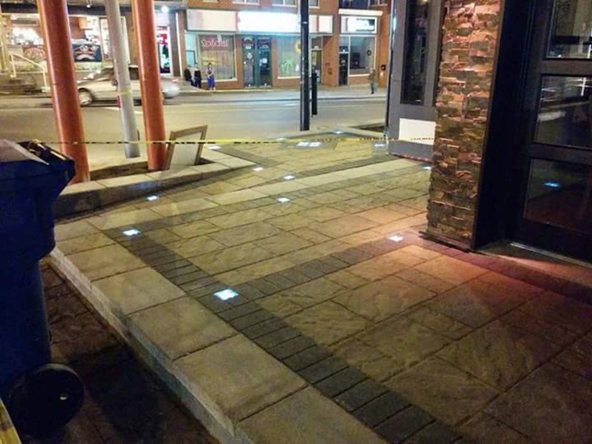 Une poubelle est posée sur le trottoir devant un bâtiment la nuit.