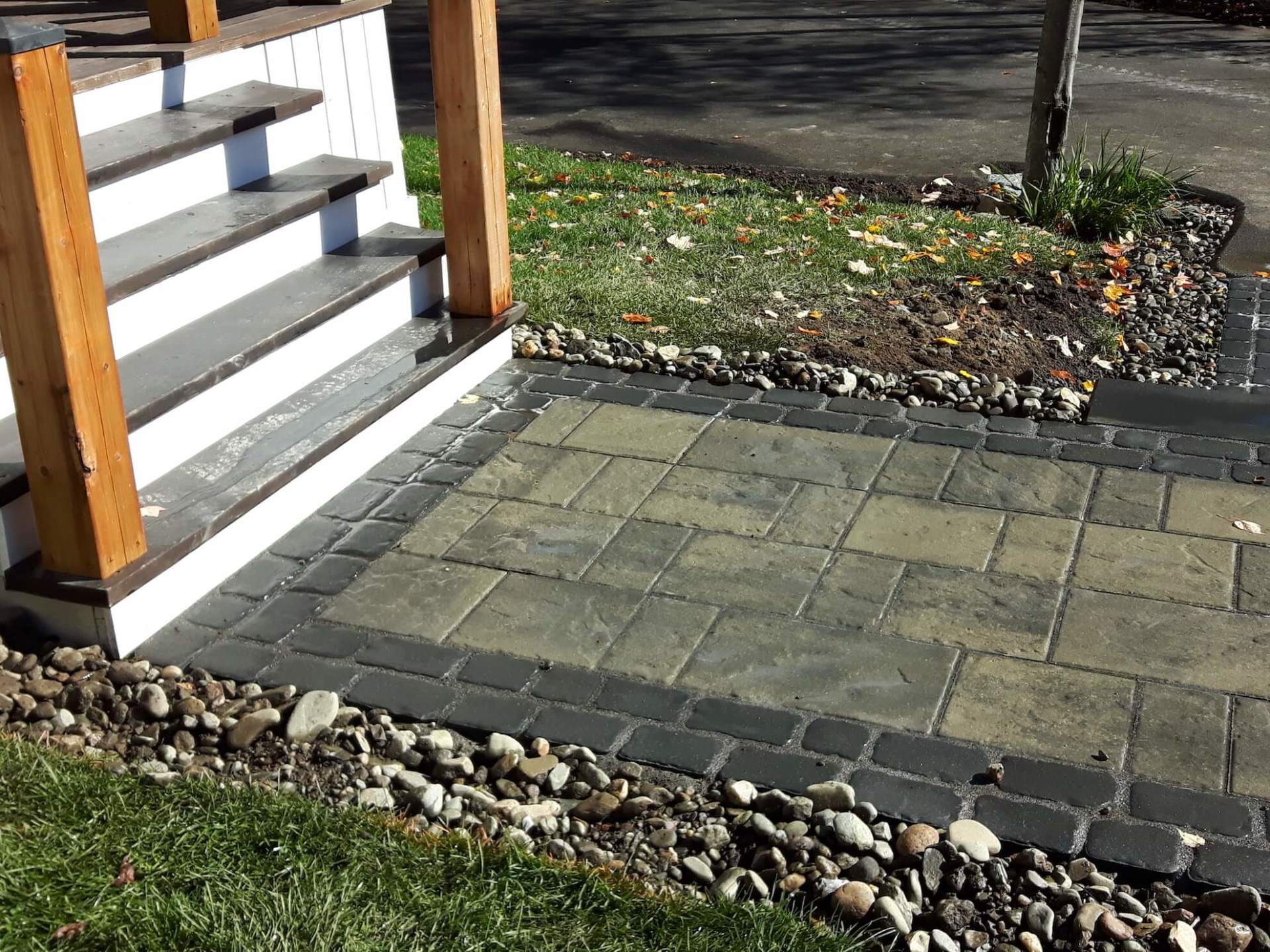 Une allée en pierre menant à un porche avec des escaliers et une balustrade en bois.