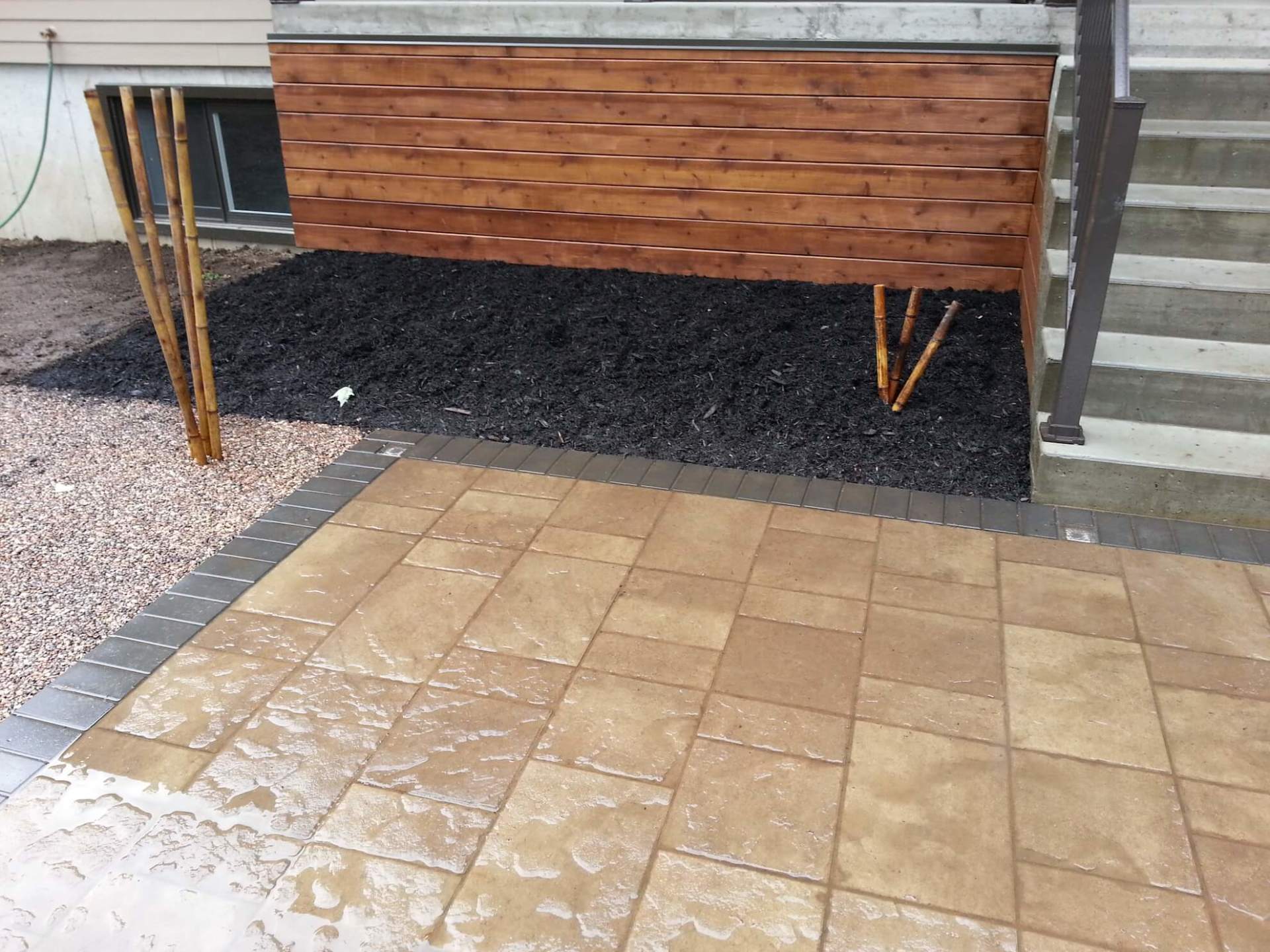 Un patio avec une clôture en bois et des escaliers en arrière-plan